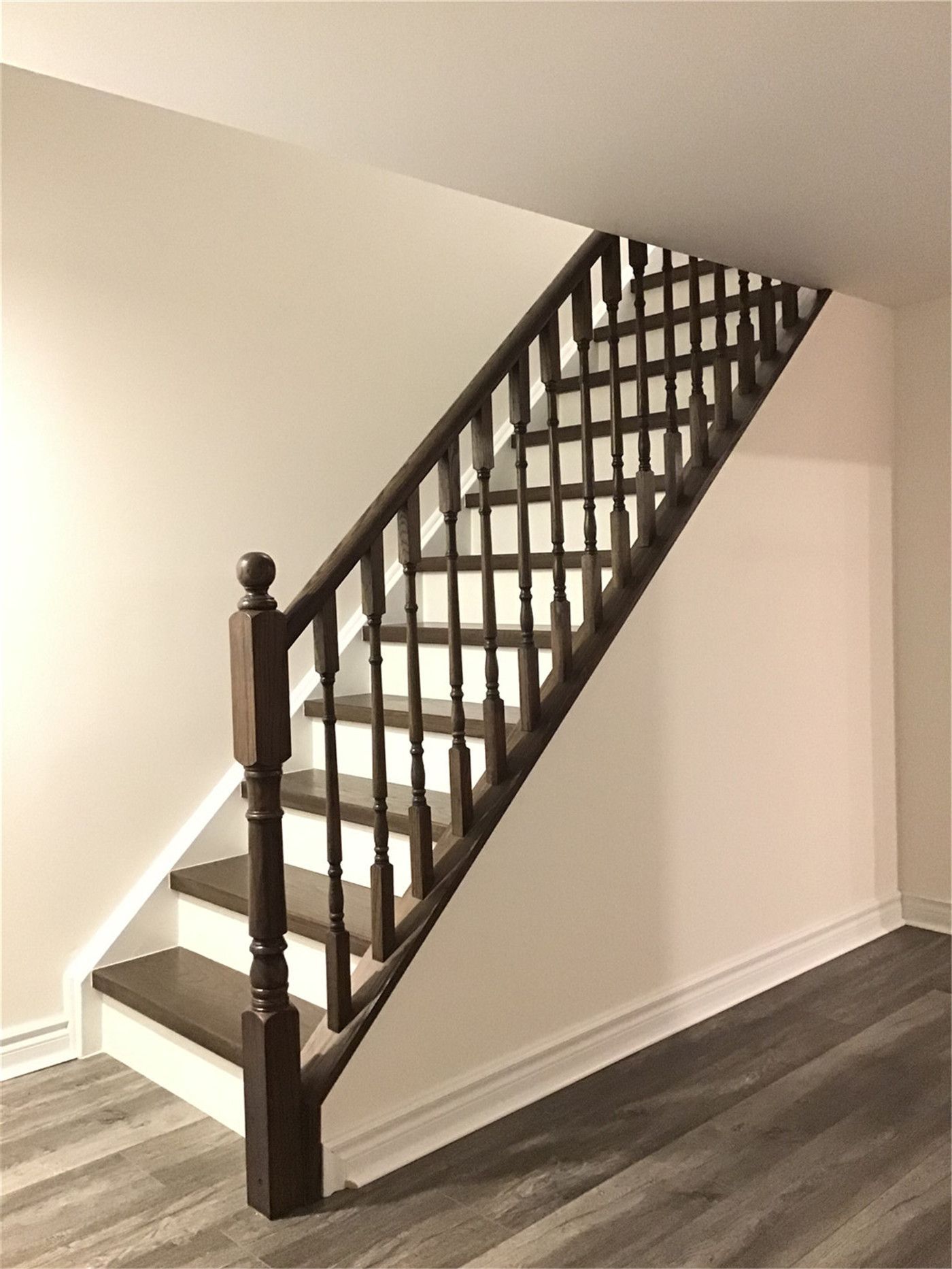 Custom-built wood staircase with dark-stained handrails and spindles completed in this Richmond Hill basement renovation. The upgraded stair system enhances safety, durability, and visual appeal while seamlessly matching the modern vinyl plank flooring throughout the finished basement.