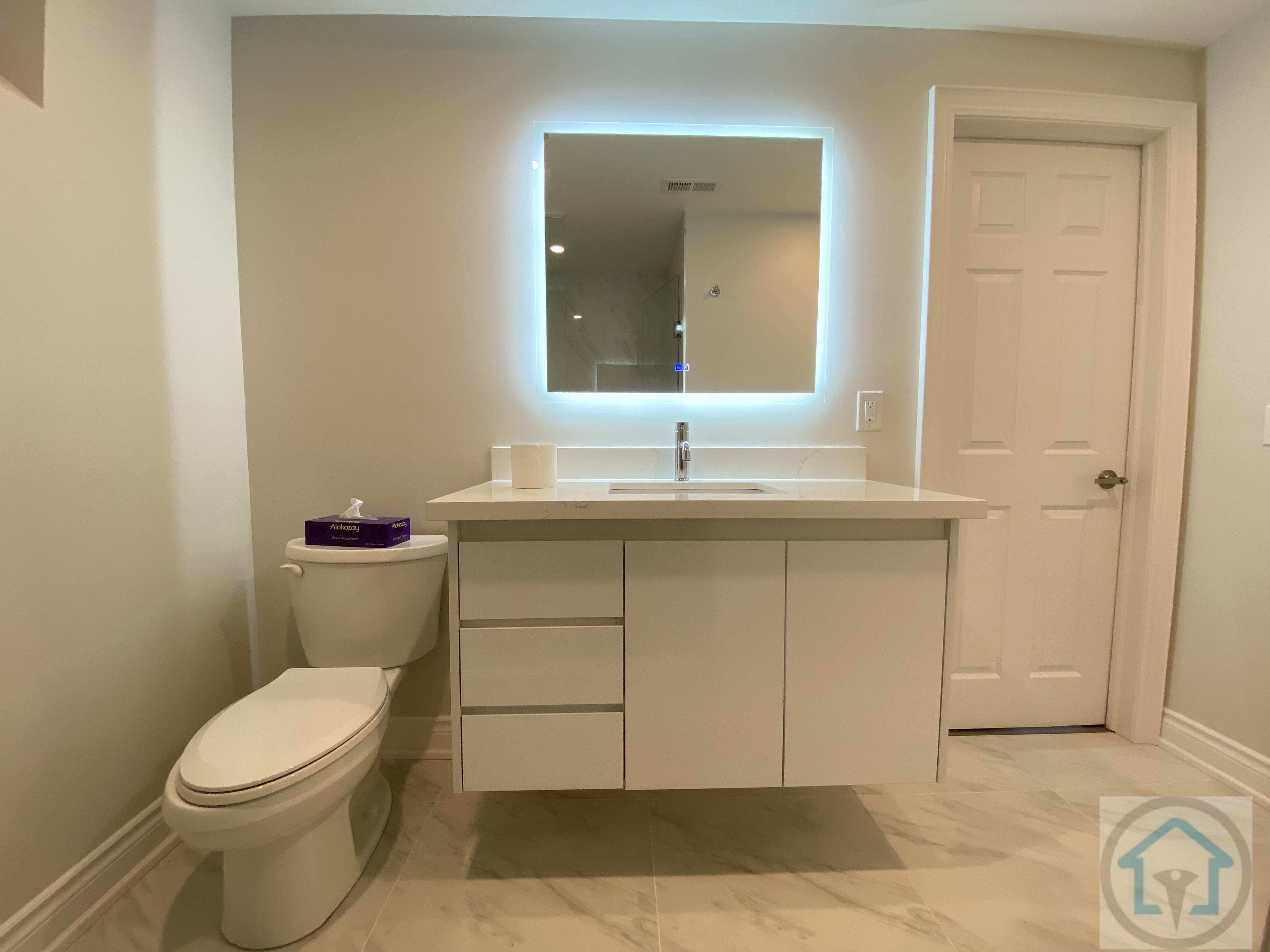 This Newmarket basement renovation includes a modern bathroom vanity with integrated storage, a clean-lined countertop, and an LED backlit mirror that enhances both lighting and functionality. Neutral finishes and durable flooring create a bright, practical basement bathroom designed for everyday use.