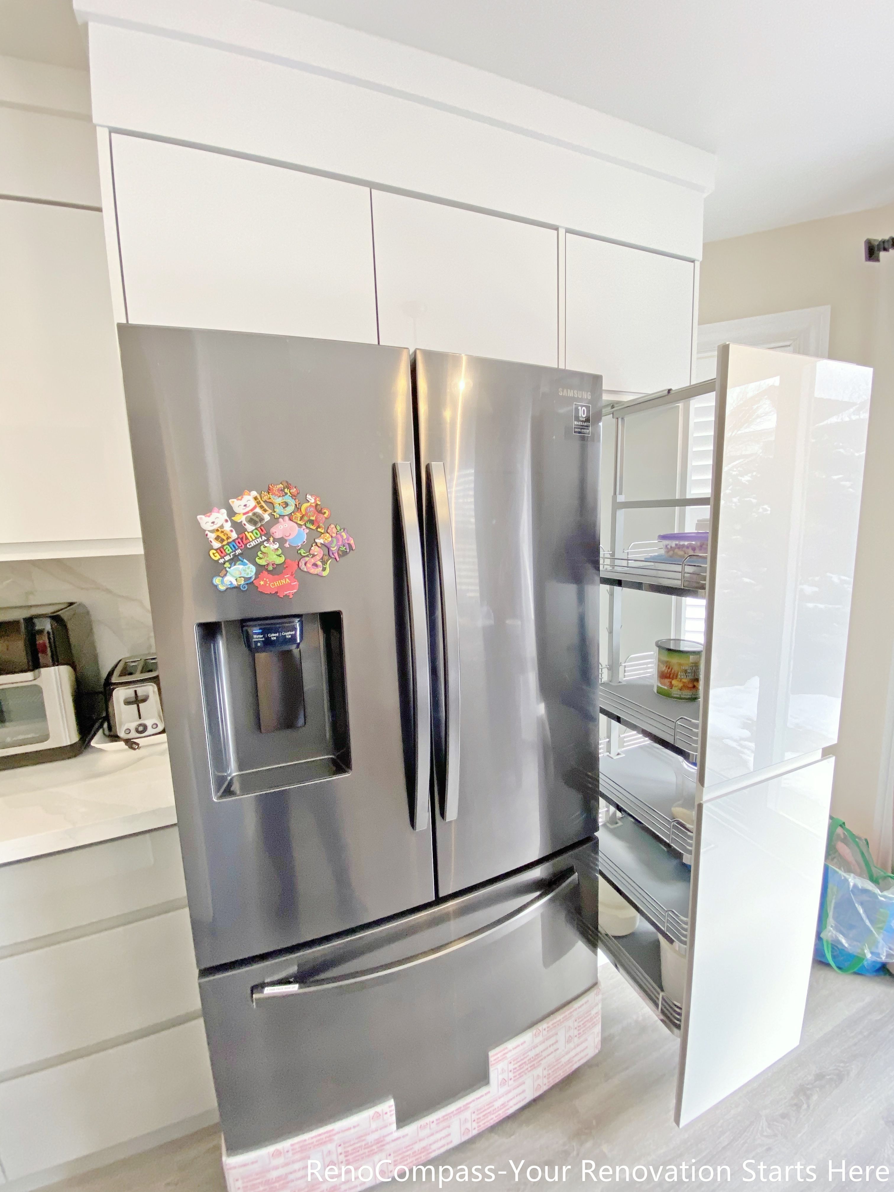 This image features an integrated refrigerator wall as part of a Mississauga kitchen renovation. The design combines a stainless steel French-door refrigerator with surrounding full-height cabinetry and a tall pull-out storage unit, maximizing vertical storage and improving organization. The cabinet layout allows appliances to sit flush with the surrounding millwork, creating a clean and cohesive look. This practical configuration enhances accessibility and storage efficiency while maintaining a modern, streamlined appearance in the kitchen.