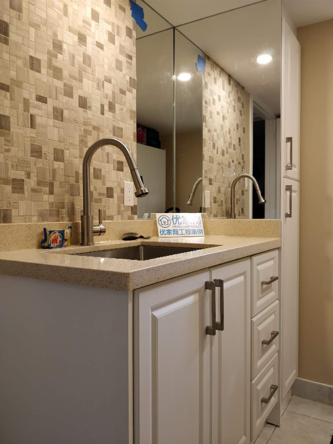 Stylish basement wet bar area completed as part of a Scarborough interior renovation. The design features custom white cabinetry, quartz countertop, modern pull-down faucet, mosaic tile backsplash, and a large wall mirror to enhance light and depth, creating a functional and elegant entertainment space for the home.