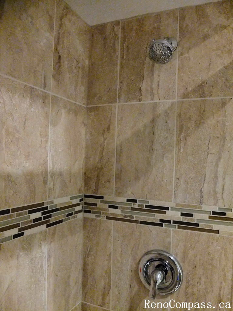 Shower valve detail from a North York bathroom renovation, featuring polished chrome fixtures and vertically patterned wall tiles for a clean, cohesive, and practical shower design.