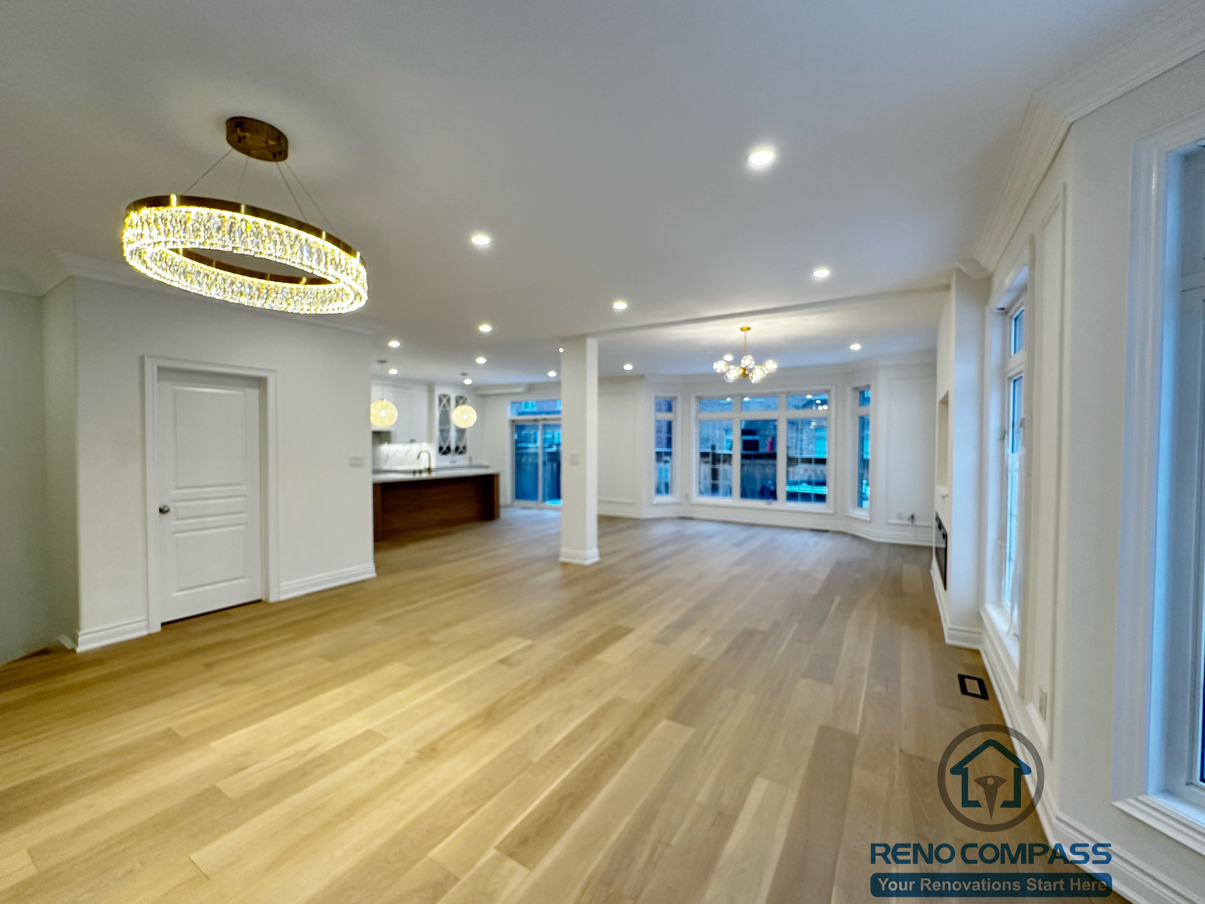 Spacious open-concept living and dining area completed as part of a Vaughan interior renovation, featuring wide-plank hardwood flooring, recessed ceiling lights, modern chandelier, and large windows that bring in natural light. The layout enhances flow, brightness, and functionality, reflecting the quality workmanship of a professional Toronto renovation company.