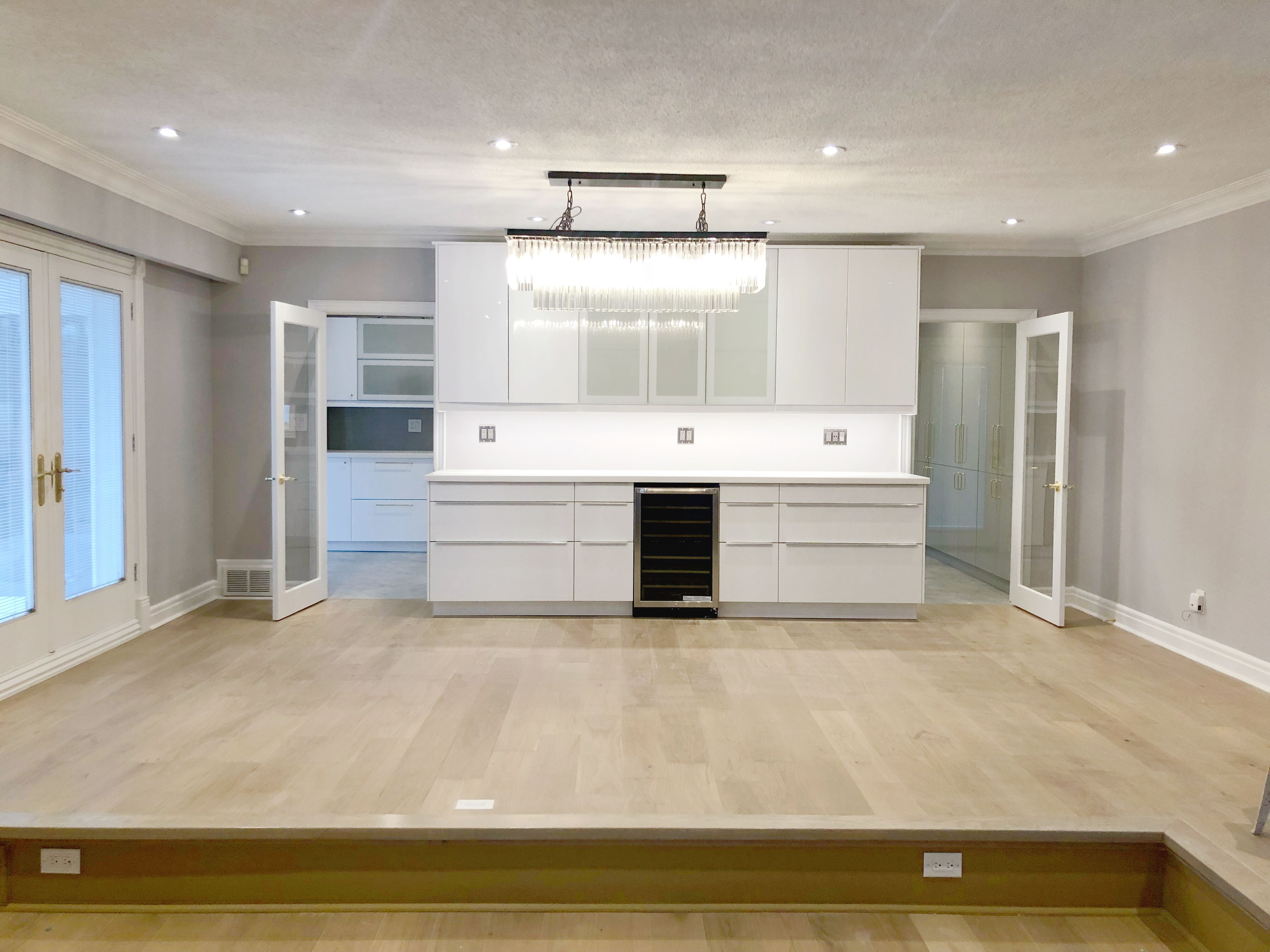 This Etobicoke interior renovation showcases a spacious open-concept living area with custom-built cabinetry, modern lighting, and upgraded flooring for a clean and refined look. The feature wall with integrated storage and wine cooler enhances both functionality and visual balance, while recessed lighting and large windows improve overall brightness. Designed and completed by Reno Compass Inc., this renovation focuses on modern comfort, practical layout planning, and timeless finishes that elevate everyday living.