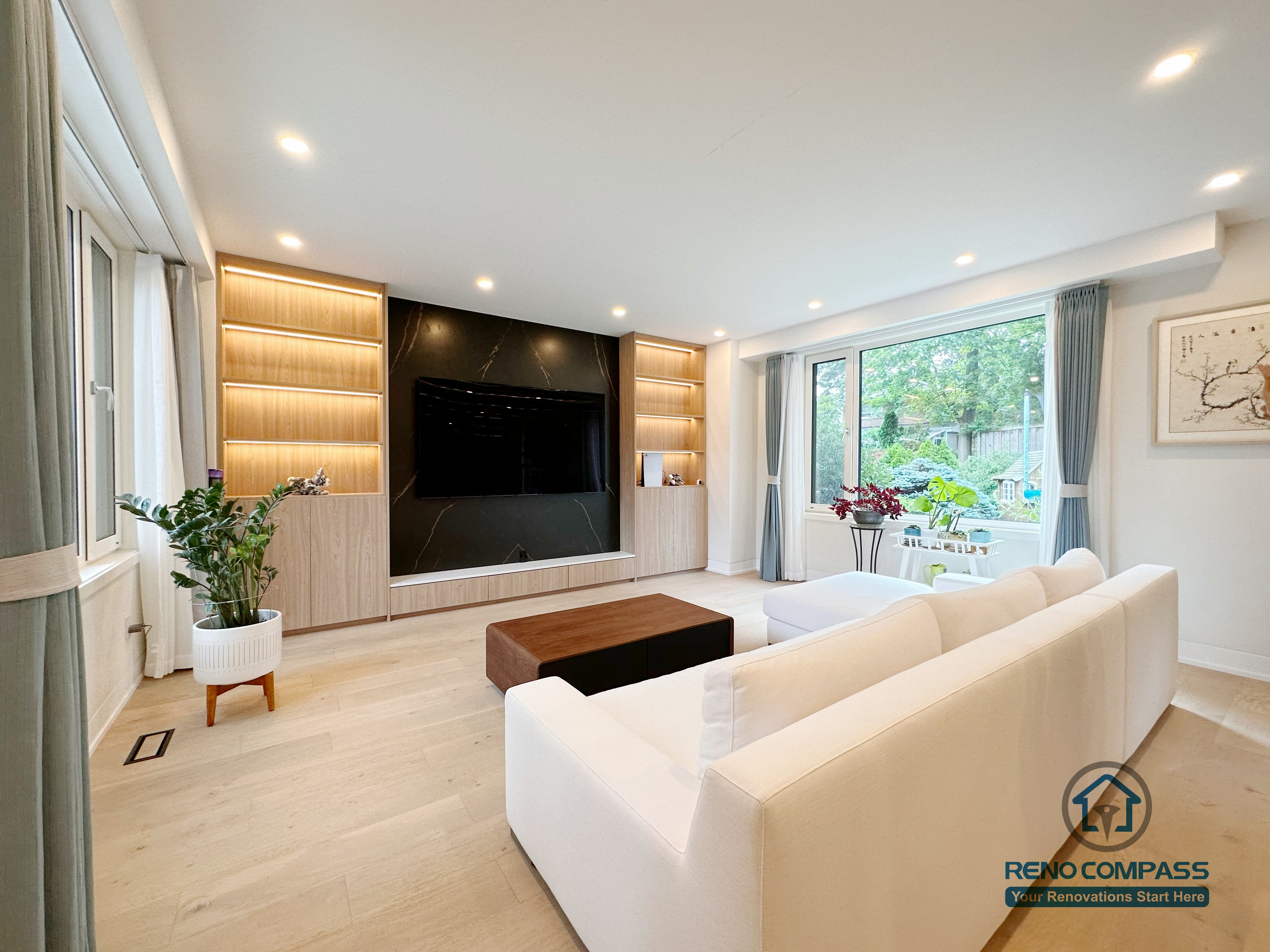A modern living room renovation in Toronto featuring a custom media wall with built-in cabinetry and symmetrical display shelving. Integrated LED lighting and clean wood finishes create a balanced, minimalist focal point while enhancing storage and visual harmony. This whole-house custom cabinetry project was completed by a professional Toronto renovation company.