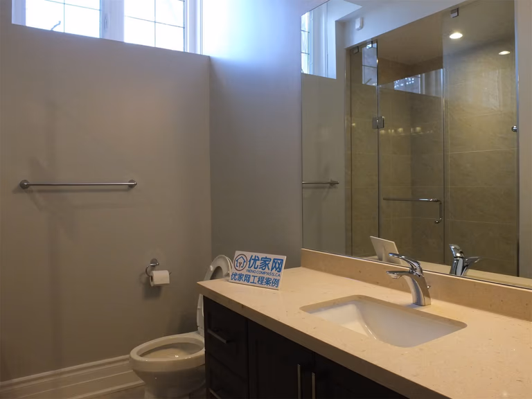 This Richmond Hill basement renovation features a modern bathroom design with a glass-enclosed shower, sleek vanity, and quartz countertop. The clean layout and neutral tones create a bright and functional space, ideal for a finished basement or rental unit.
