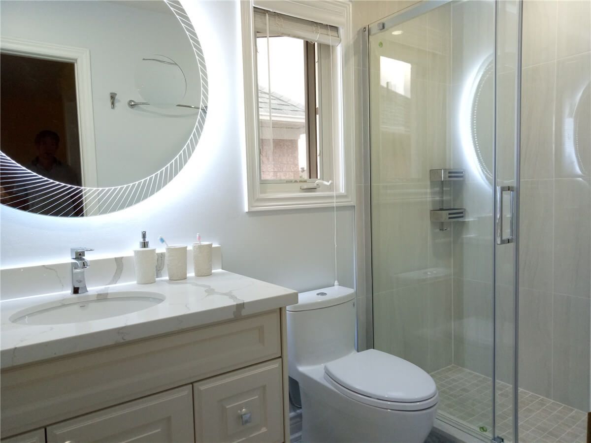 This Richmond Hill bathroom renovation highlights a bright and modern layout featuring a custom vanity with quartz countertop, illuminated LED mirror, and a sleek frameless glass shower enclosure. Neutral tones and quality finishes create a clean, spa-like environment while maximizing functionality and comfort. The upgraded fixtures and efficient space planning bring a fresh contemporary feel, enhancing both daily living and long-term home value through thoughtful interior renovation.