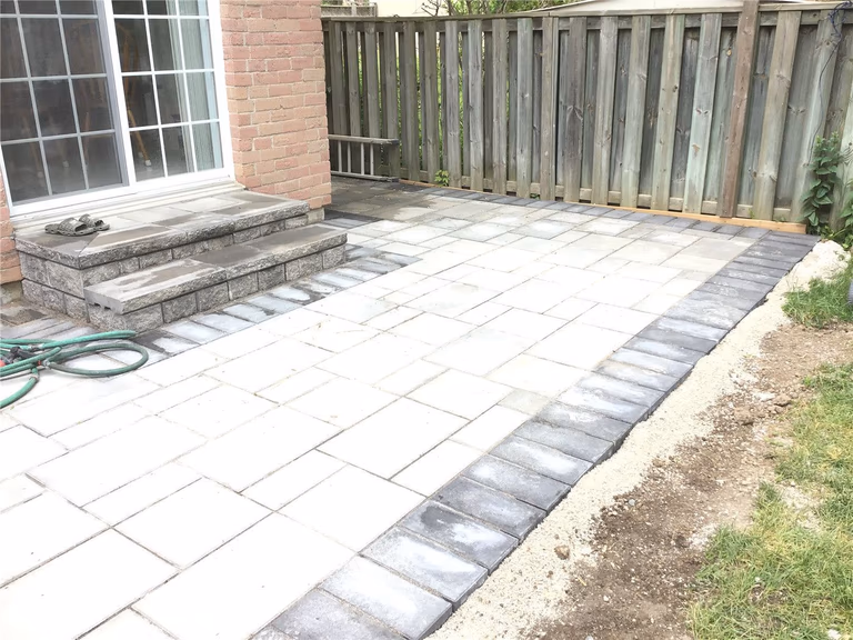 This Oakville interlocking project features a beautifully designed front entrance patio with curved stone steps, modern grey pavers, and a seamless transition from walkway to porch. The layout enhances both curb appeal and functionality, providing a clean, durable outdoor space that complements the home’s brick exterior. Ideal for homeowners looking to upgrade their entrance with elegant and long-lasting interlocking stonework.