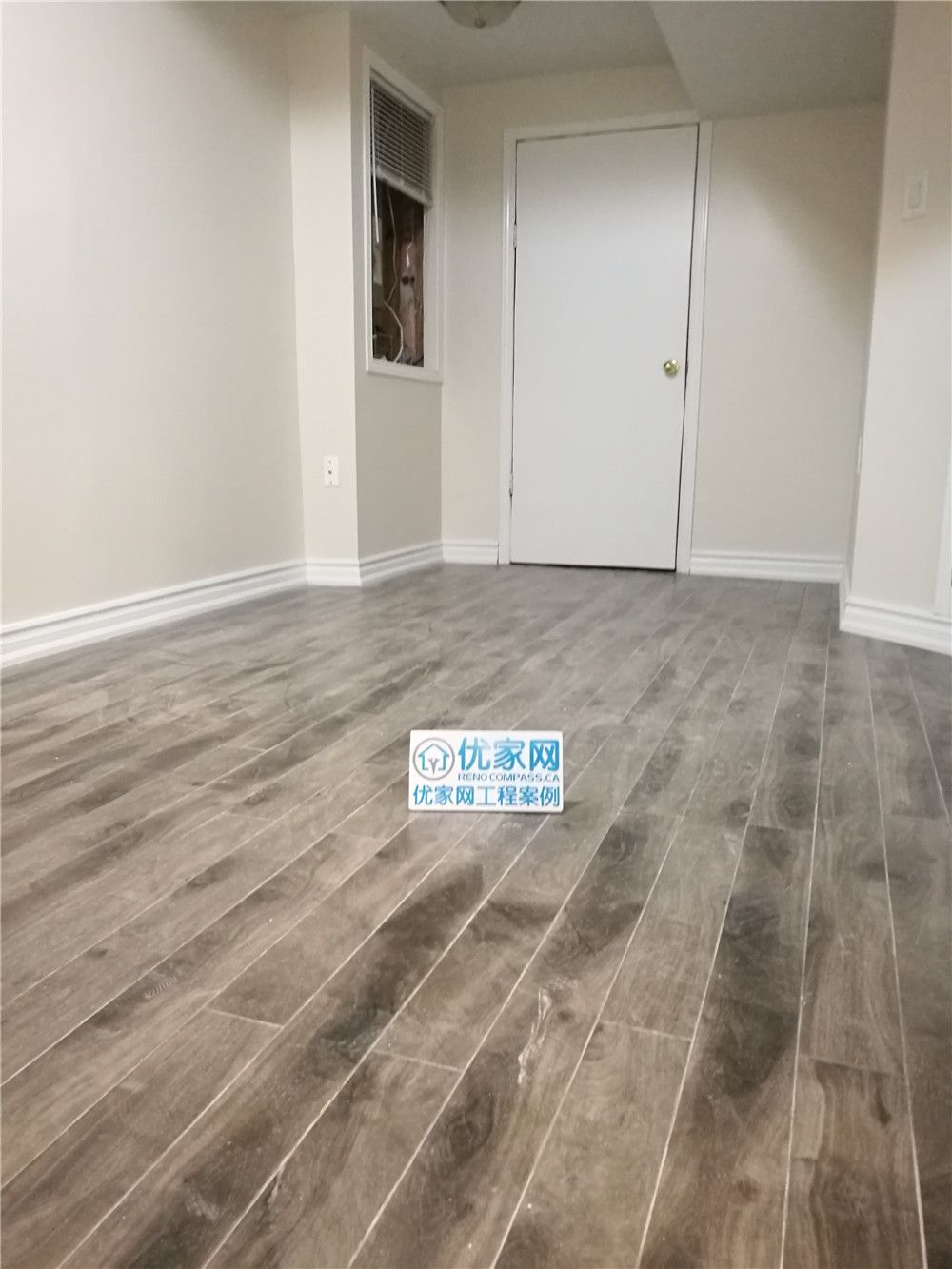 This image showcases a finished basement bedroom space from a Markham basement renovation project. The room features durable wood-look flooring, neutral wall tones, and clean trim details that create a bright and comfortable living environment. The modern flooring enhances both visual warmth and long-term durability, making the space ideal for a guest bedroom, rental suite, or home office. Completed by a professional Toronto Renovation Company, this basement renovation emphasizes functional layout planning, moisture-resistant materials, and contemporary interior finishes to improve overall property value and everyday comfort.