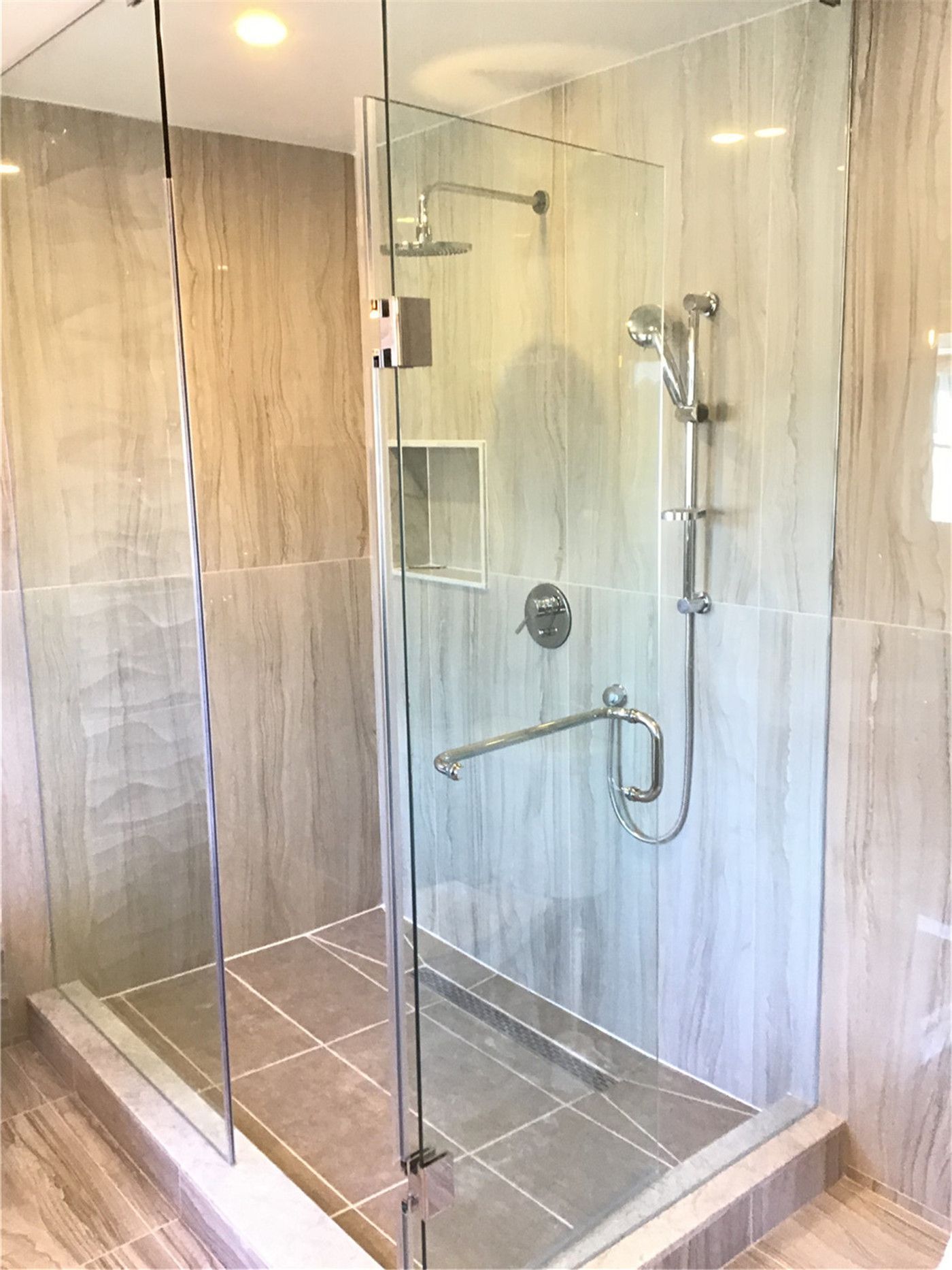 This Woodbridge bathroom renovation features a modern walk-in shower with a frameless glass enclosure, built-in wall niche, and safety grab bar. The design combines accessibility, comfort, and contemporary style, making it ideal for both everyday use and long-term convenience.