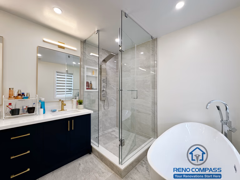 Master bathroom renovation in Markham featuring a frameless glass shower, large-format tile finishes, a custom vanity with matte black cabinetry, and brass fixtures. The design combines clean lines, efficient layout, and a refined modern aesthetic for everyday comfort.