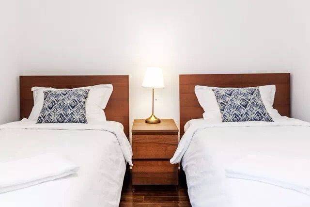 This Toronto interior renovation features a bright and well-organized twin bedroom layout with matching beds, warm wooden headboards, and soft neutral décor. The symmetrical design and simple furnishings create a clean, comfortable environment ideal for guests or family members. The renovation highlights a functional and welcoming bedroom space suitable for modern Toronto home living.