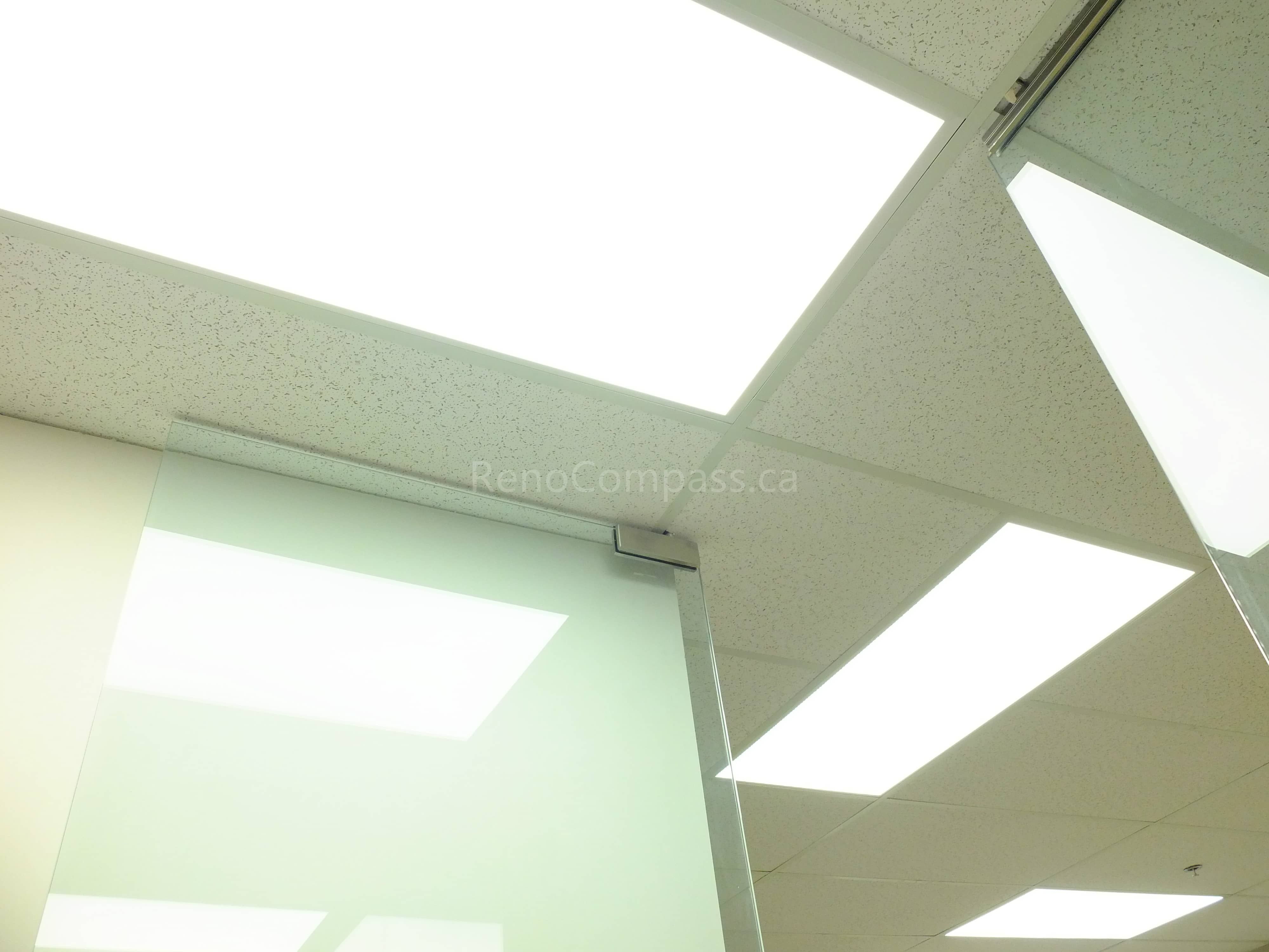 This image showcases bright LED panel lights installed in a modern North York office ceiling. The energy-efficient lighting design enhances the professional atmosphere, providing uniform illumination across the workspace while complementing the suspended acoustic ceiling system and glass office partitions.