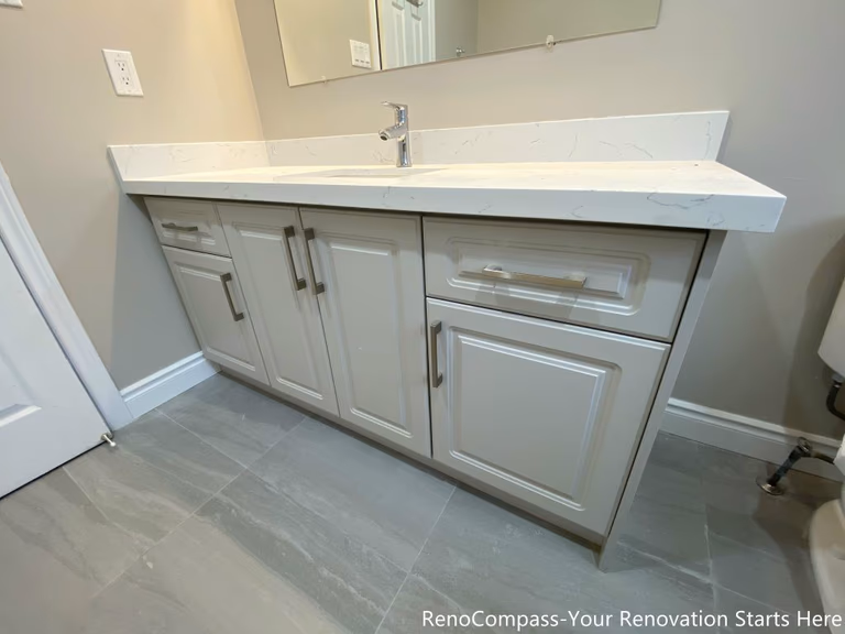 This Mississauga interior renovation highlights a modern bathroom vanity featuring a quartz countertop, soft gray cabinetry, and functional storage drawers. The clean-lined cabinet design improves organization and daily usability, while the durable countertop provides long-lasting performance. Neutral finishes and streamlined hardware create a balanced, timeless vanity solution that integrates seamlessly into the overall bathroom renovation.
