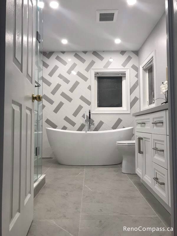 Recent bathroom renovation in Markham, Ontario. This project showcases a contemporary spa-like design with large-format floor tiles and an elegant standalone bathtub.