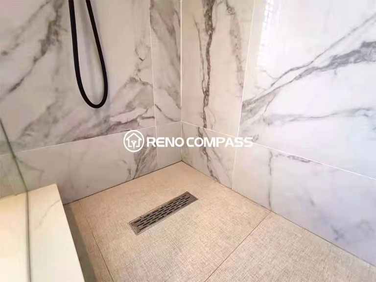 Close-up of a custom walk-in shower featuring marble-look wall tiles, a linear floor drain, and slip-resistant shower flooring. The clean tile alignment and precision installation highlight the quality workmanship of this Toronto renovation company. Designed for efficient drainage, waterproof durability, and a sleek modern finish, this bathroom renovation combines functionality with contemporary style for long-term performance.