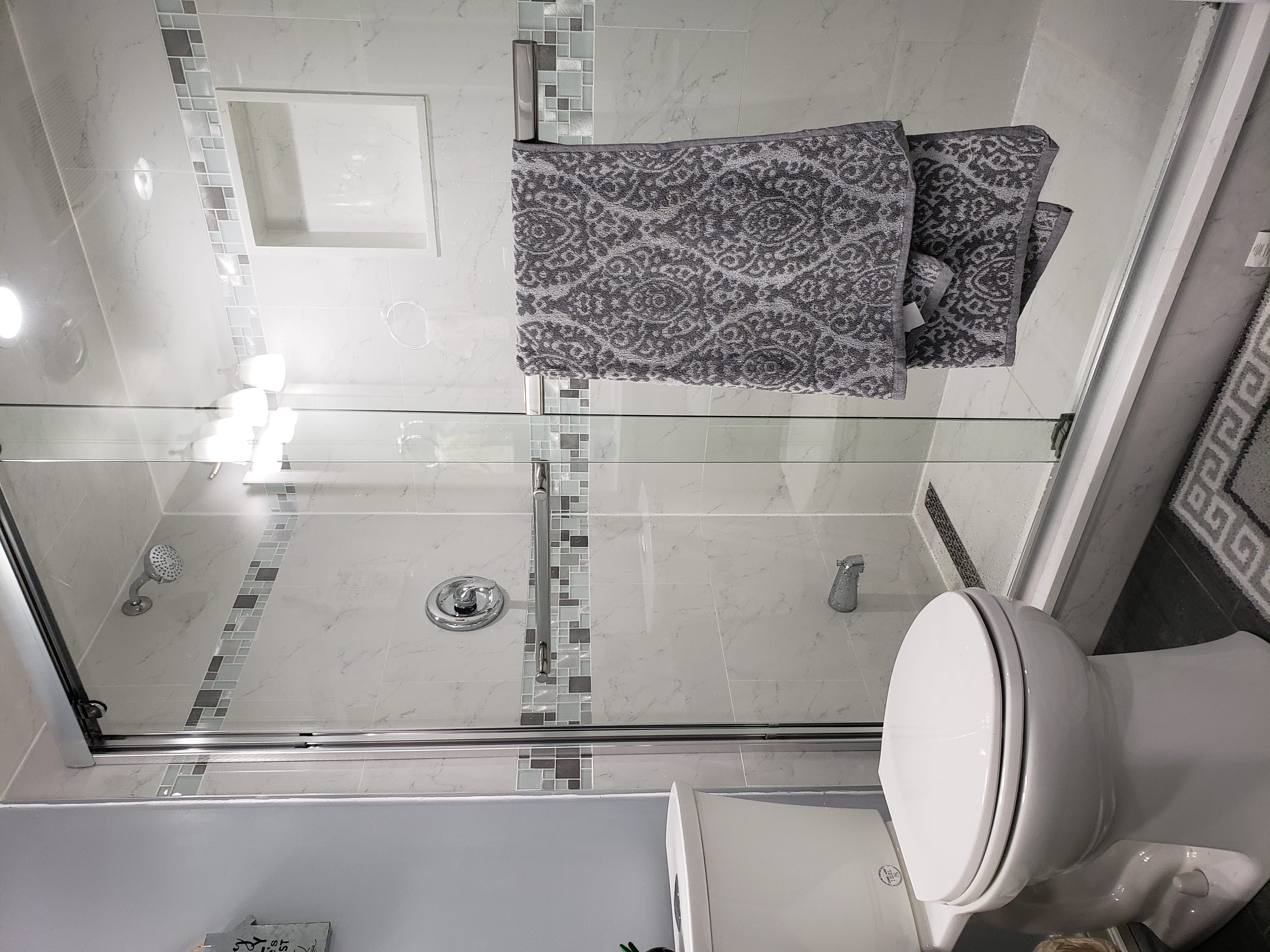 This basement bathroom renovation in Newmarket, Toronto features a clean and modern design with a glass-enclosed shower, full-height wall tiles, and upgraded plumbing fixtures. The shower area includes a built-in niche and decorative accent tile band, combining functionality with contemporary style. Neutral tones and bright lighting enhance the sense of space, making the bathroom feel fresh and inviting despite the basement setting. Durable floor tiles and moisture-resistant materials ensure long-term performance and easy maintenance. Completed by a professional Toronto renovation company, this basement bathroom upgrade focuses on practicality, comfort, and modern interior aesthetics.