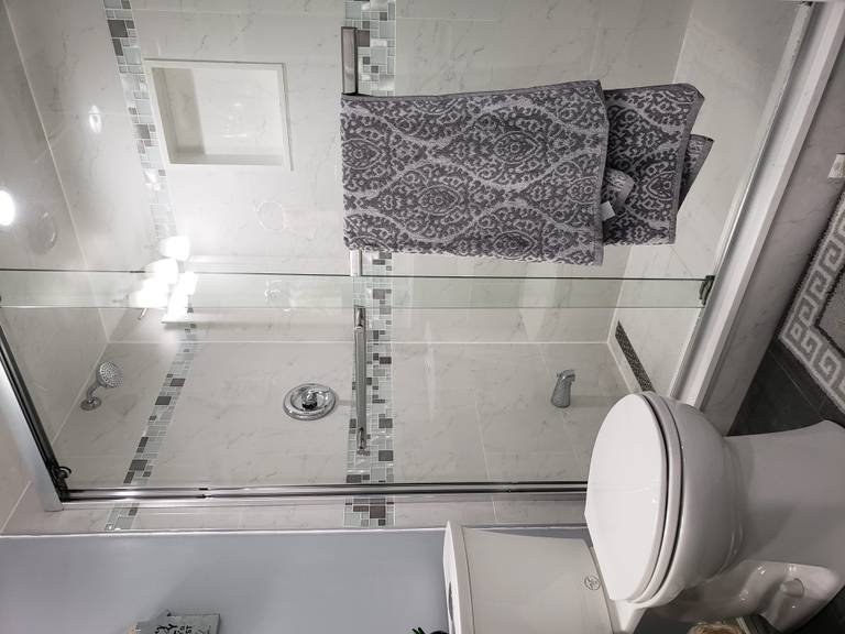 This basement bathroom renovation in Newmarket, Toronto features a clean and modern design with a glass-enclosed shower, full-height wall tiles, and upgraded plumbing fixtures. The shower area includes a built-in niche and decorative accent tile band, combining functionality with contemporary style. Neutral tones and bright lighting enhance the sense of space, making the bathroom feel fresh and inviting despite the basement setting. Durable floor tiles and moisture-resistant materials ensure long-term performance and easy maintenance. Completed by a professional Toronto renovation company, this basement bathroom upgrade focuses on practicality, comfort, and modern interior aesthetics.
