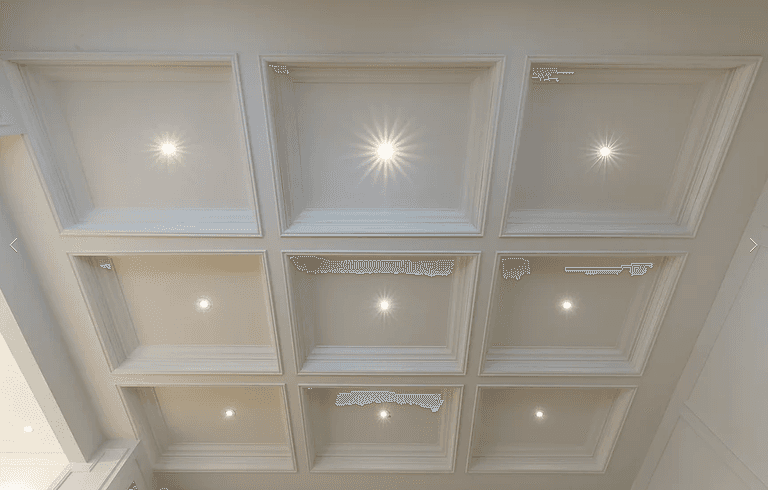 This Richmond Hill interior renovation highlights a refined living space with a coffered ceiling, custom wainscoting, and detailed hardwood flooring with inlay borders. Large windows with plantation shutters enhance natural light, while classic millwork and clean architectural lines create a timeless, elegant interior renovation result.
