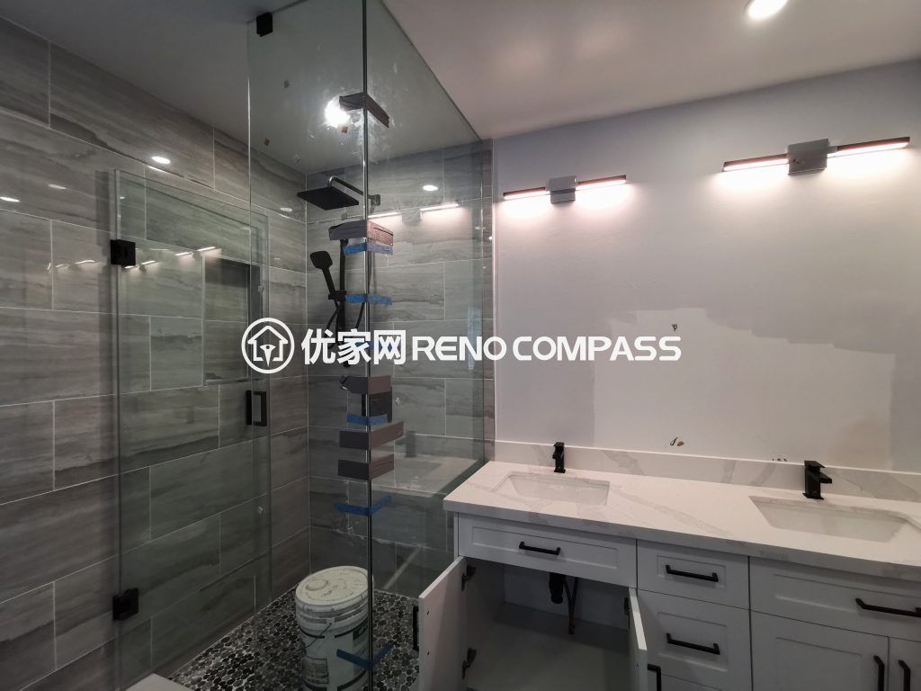Richmond Hill bathroom renovation featuring a frameless glass walk-in shower, double sink vanity with quartz countertop, and modern wall-mounted lighting. Large-format tiles and sleek fixtures create a bright, functional, and contemporary bathroom space completed by a professional Toronto renovation company.