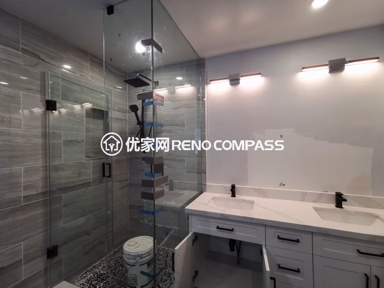 Richmond Hill bathroom renovation featuring a frameless glass walk-in shower, double sink vanity with quartz countertop, and modern wall-mounted lighting. Large-format tiles and sleek fixtures create a bright, functional, and contemporary bathroom space completed by a professional Toronto renovation company.