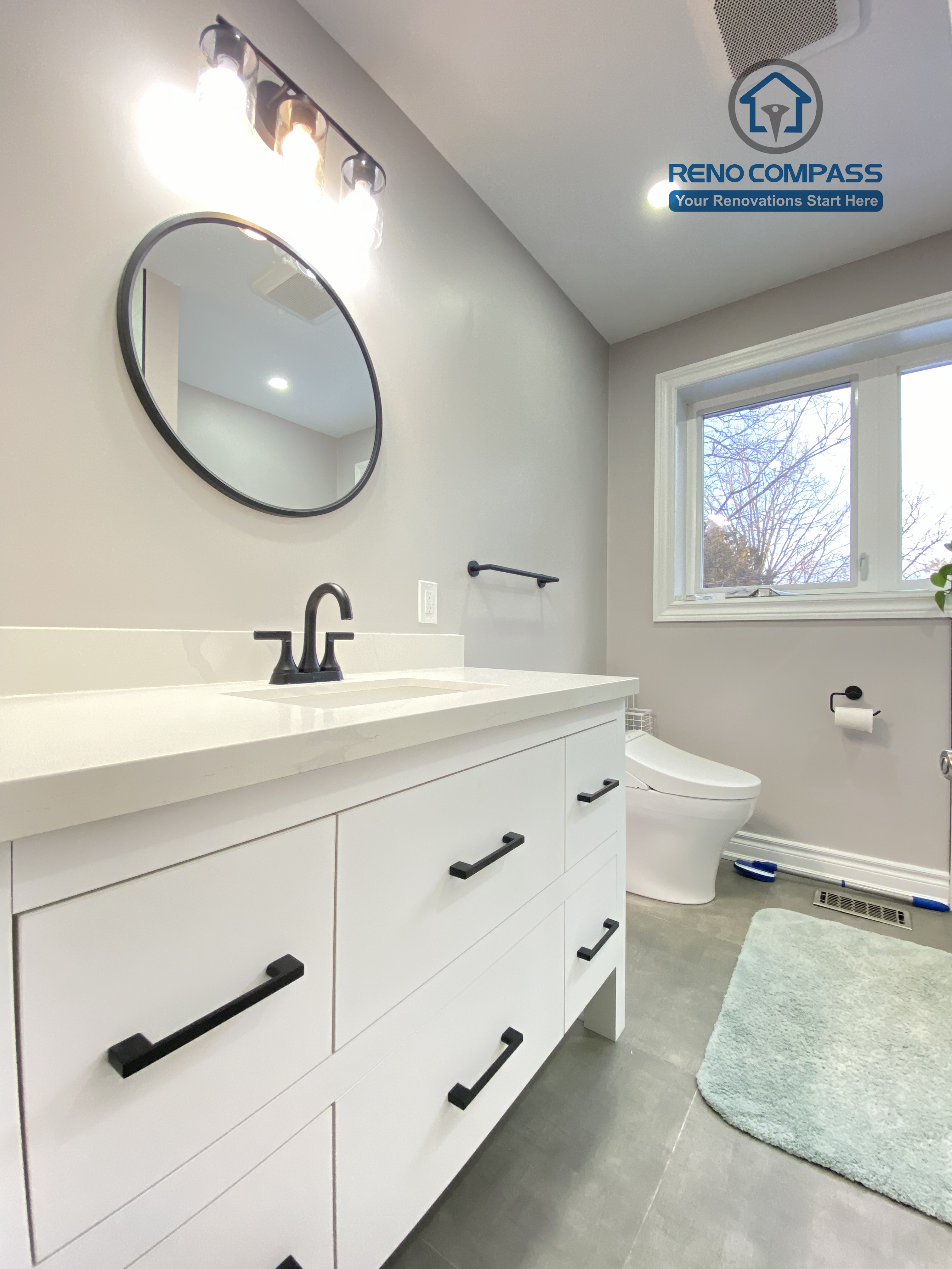 This North York bathroom renovation highlights a modern double-drawer vanity paired with a quartz countertop, matte black faucet, and matching hardware. The round mirror and wall-mounted lighting enhance both functionality and visual balance, creating a clean and efficient bathroom space completed by a Toronto renovation company focused on quality materials and precise installation.
