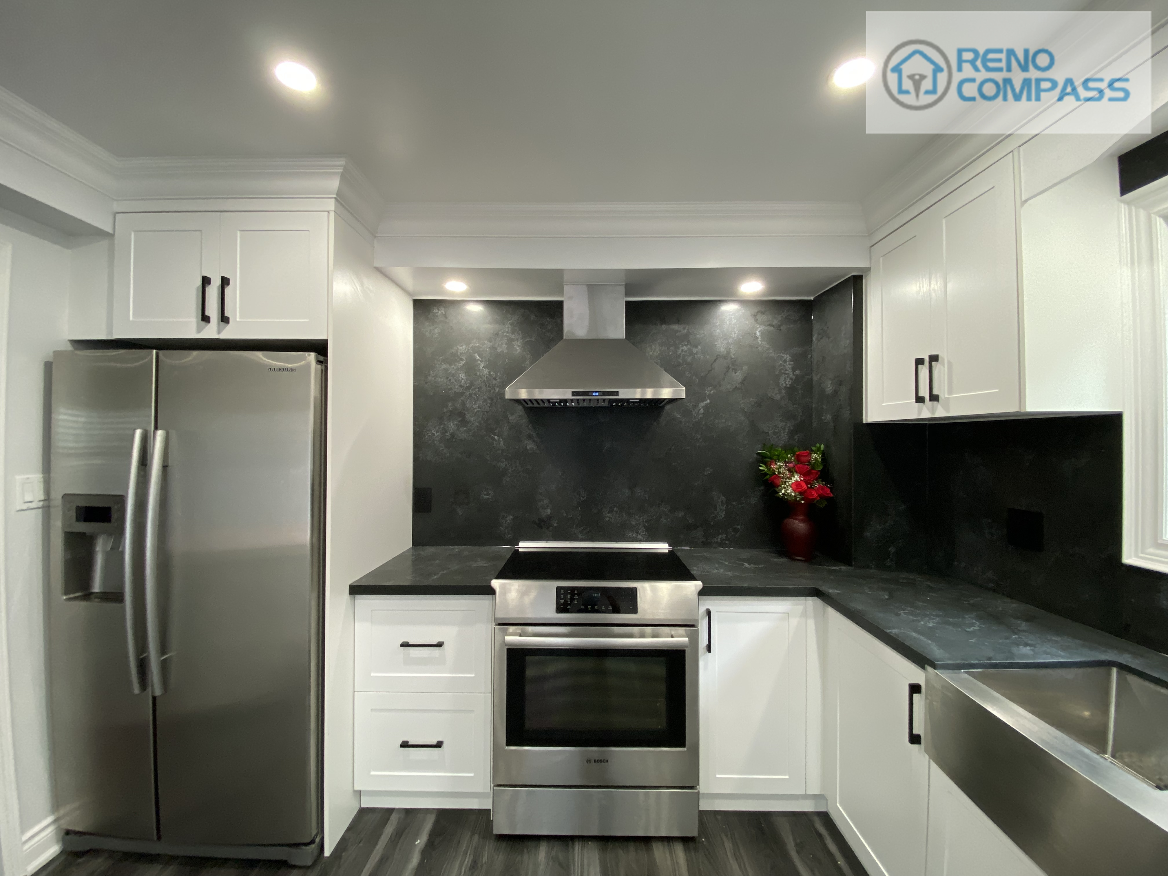 This modern kitchen interior renovation in Pickering features white shaker cabinets, black stone backsplash, quartz countertops, stainless steel appliances, and a farmhouse-style sink. Designed and built by Reno Compass Inc., this project showcases clean lines, efficient layout, and durable materials ideal for everyday family living.