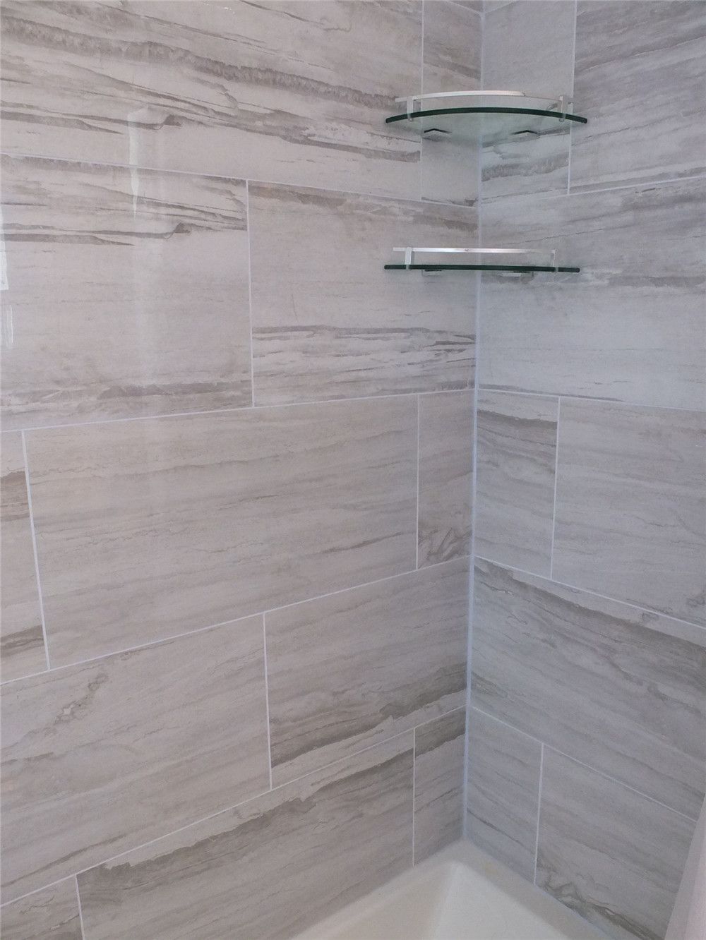 This North York bathroom renovation features modern porcelain wall tile installation in the shower area, creating a durable and moisture-resistant bathing space. The design includes built-in glass corner shelves for convenient storage and a clean contemporary appearance. Completed by a professional Toronto renovation company, the upgraded shower area combines practical functionality with a bright and elegant bathroom design.