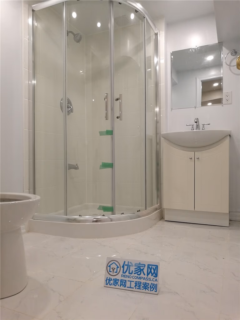 his image showcases a newly completed basement bathroom renovation in Markham. The space features a modern curved glass shower enclosure paired with sleek chrome fixtures, creating a bright and contemporary look. Light marble-style flooring enhances the sense of space while improving durability and moisture resistance. A compact vanity with integrated storage maximizes functionality, making the bathroom ideal for guest use or basement living areas. Completed by a professional Toronto Renovation Company, this project highlights quality waterproofing, efficient layout design, and clean modern finishes for long-lasting performance.