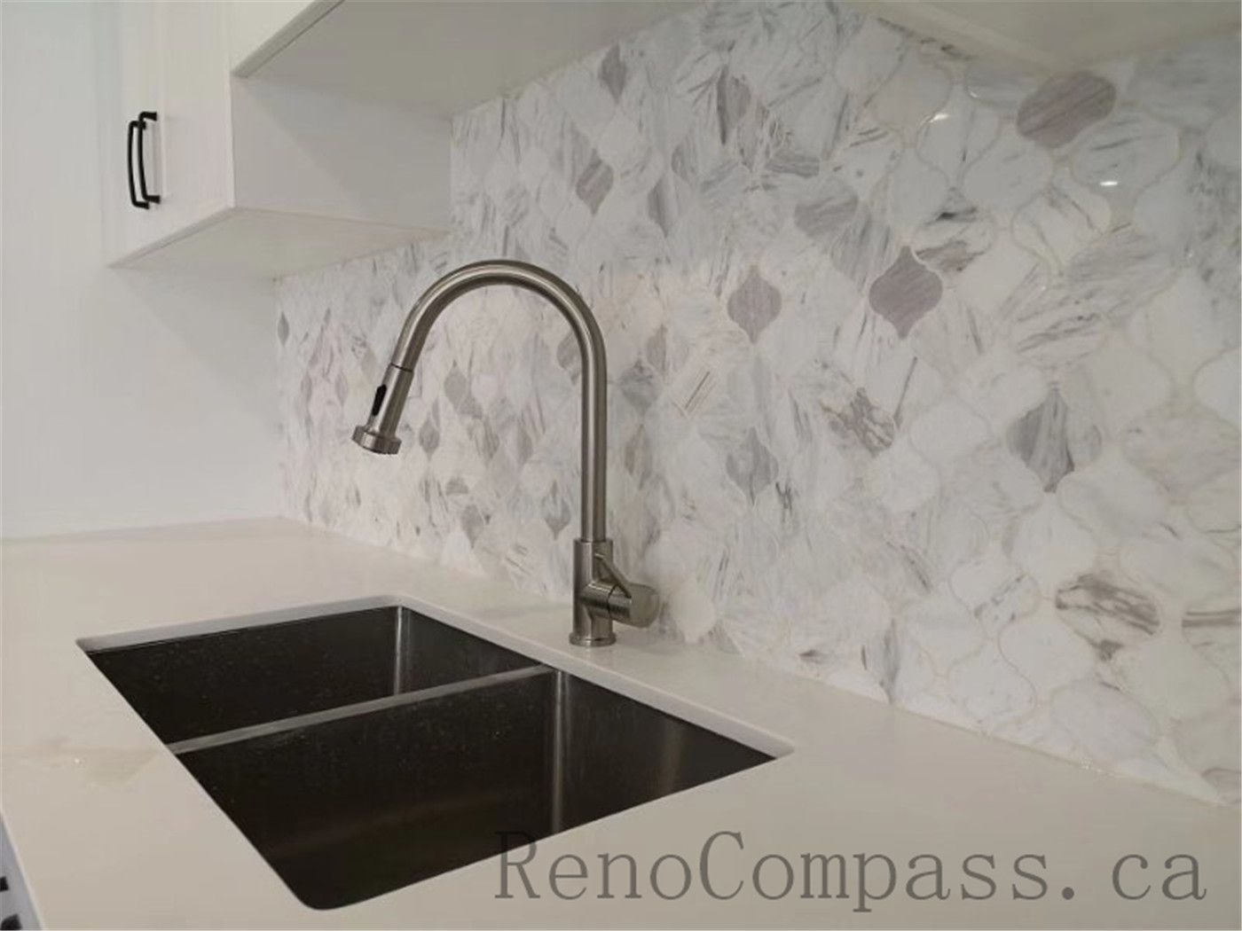 This elegant kitchen renovation in Aurora features a sleek stainless-steel faucet, a dual-basin sink, and a white marble backsplash for a polished, modern look. Designed and completed by Reno Compass.