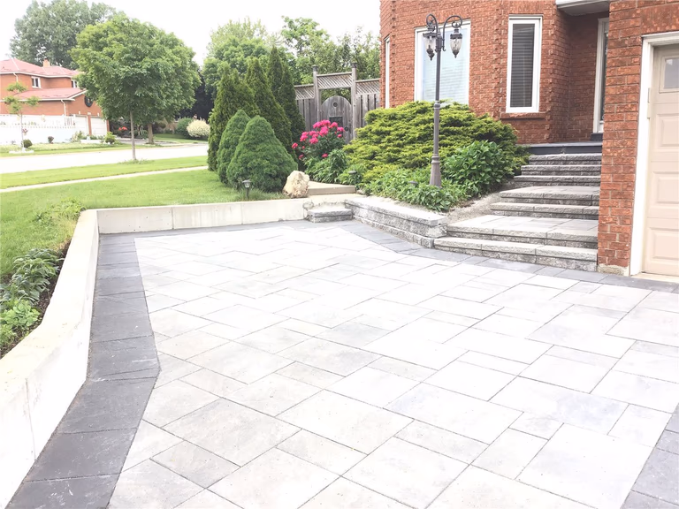 This Mississauga landscaping renovation features a professionally installed interlocking driveway with a modern grey tone and clean border design. The project enhances curb appeal while ensuring durability, proper drainage, and long-term low maintenance.
