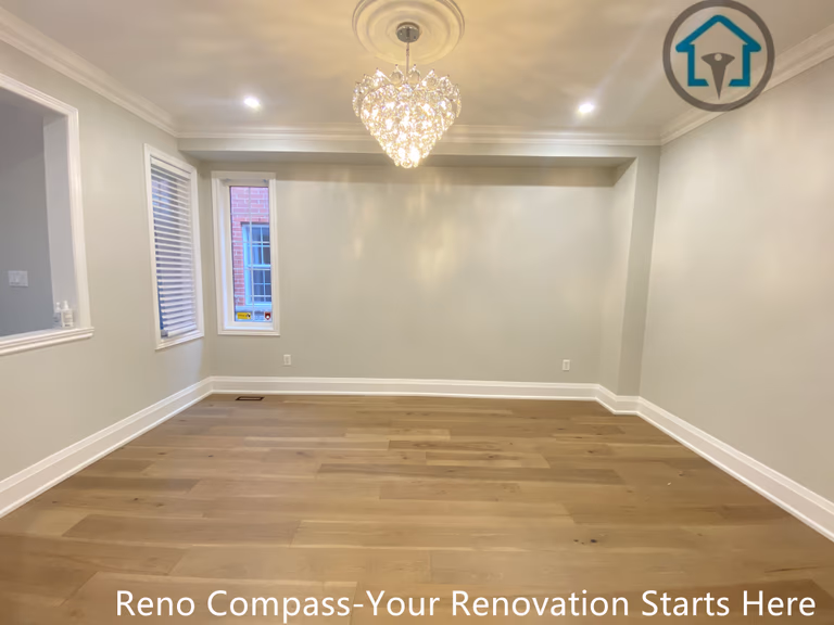 This image presents a spacious living area completed as part of a hardwood flooring renovation project in Richmond Hill. The room features wide-plank hardwood flooring, soft neutral wall tones, and refined trim details that enhance the overall sense of balance and openness. A modern chandelier and recessed lighting add warmth and visual interest while maintaining a clean, contemporary look. Completed by a professional Toronto renovation company, this renovation emphasizes material quality, natural light, and a timeless interior finish designed for everyday living.
