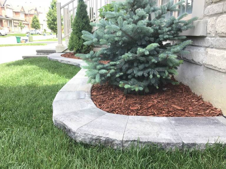 This Markham outdoor landscaping project features a beautifully installed curved stone retaining wall designed to define the garden bed and enhance the front yard landscape. The natural grey interlocking blocks create a clean border between the lawn and planting area while improving soil retention and drainage. As a professional Toronto Renovation Company, Reno Compass Inc. delivers precise landscaping construction that combines durability, functionality, and elegant curb appeal for residential properties across the Greater Toronto Area.