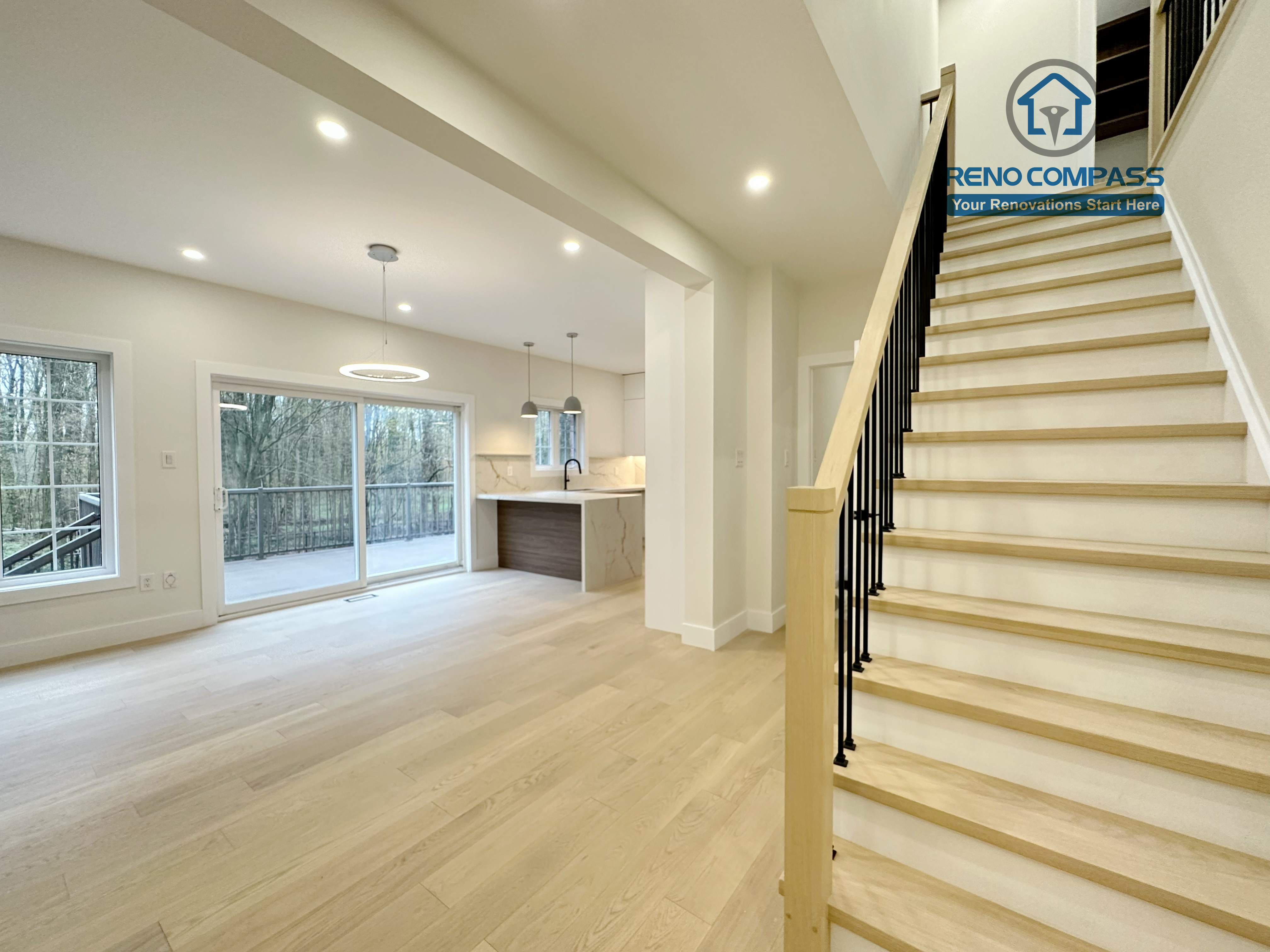 Open-concept main floor renovation in a Richmond Hill home featuring light-tone hardwood flooring, a modern staircase with wood treads and black railings, large windows for natural light, and a seamless connection to the kitchen and dining area.