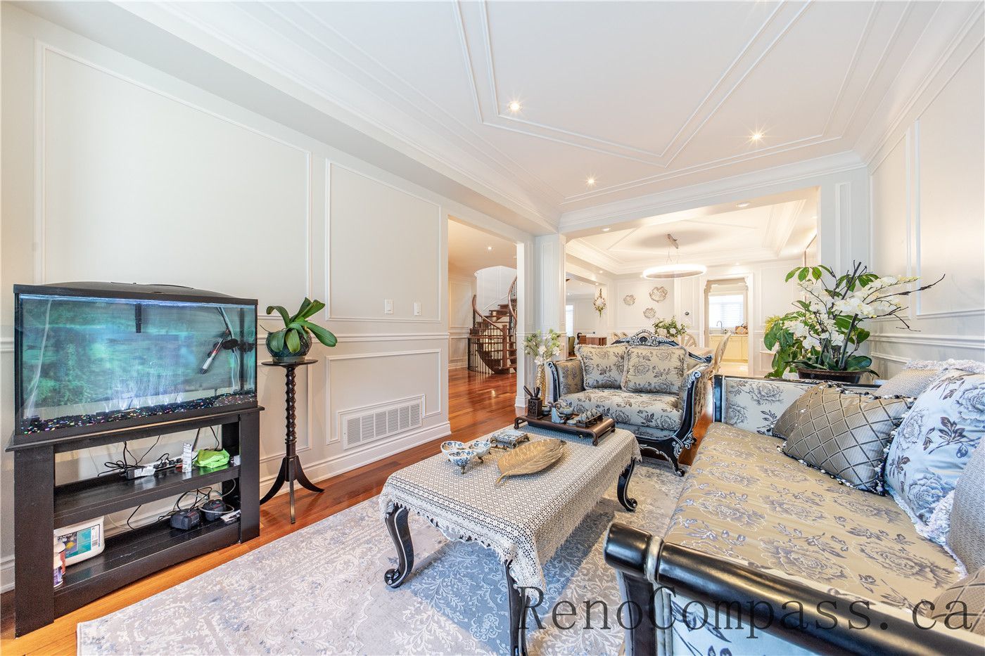 This Richmond Hill entire house interior renovation showcases a refined living room with custom wall paneling, elegant ceiling details, and warm hardwood flooring. Large bay windows bring in abundant natural light, enhancing the open and welcoming atmosphere. Classic furniture styling combined with modern finishes creates a timeless and luxurious space, professionally completed by a trusted Toronto renovation company to elevate comfort, functionality, and visual appeal.