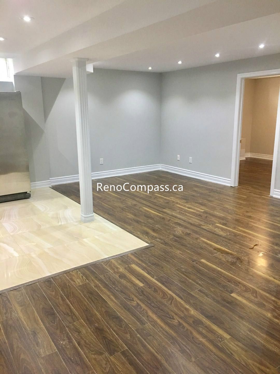 This Toronto basement renovation showcases a modern open-concept layout with newly installed wood flooring, fresh neutral wall finishes, and energy-efficient recessed pot lights. The upgraded space features structural support columns, a bright stairway area, and a clean, functional layout ideal for a family living or entertainment area. Completed by a trusted Toronto renovation company, the project highlights quality workmanship, improved lighting, and a stylish, durable basement transformation.
