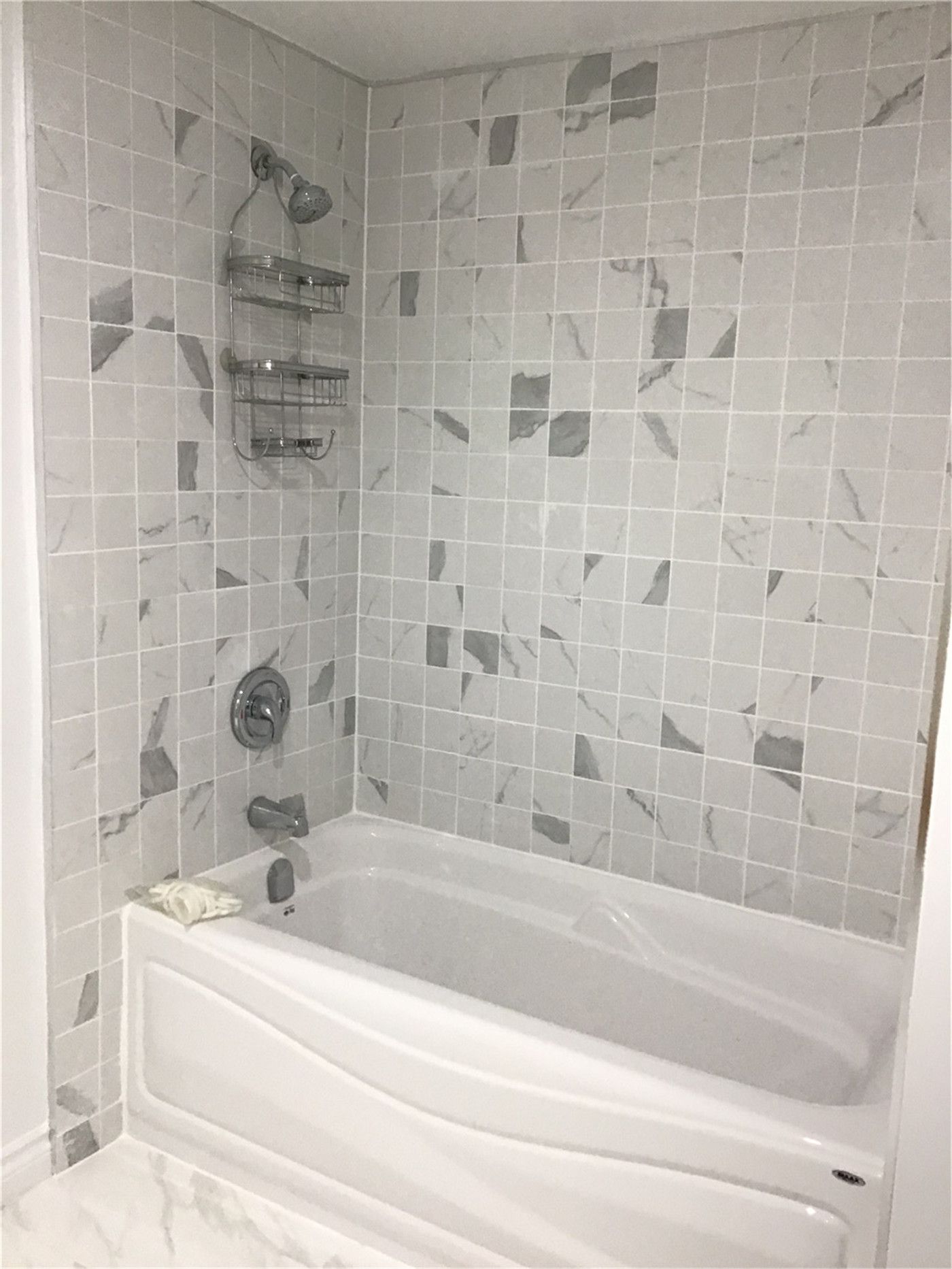 This Whitby basement renovation includes a sleek bathtub installation with a marble-pattern tile surround, creating a clean and contemporary bathroom design. The neutral-toned tiles, chrome fixtures, and built-in shelving add both style and practicality. Designed for comfort and durability, this upgraded basement bathroom enhances the functionality of the finished lower level space.