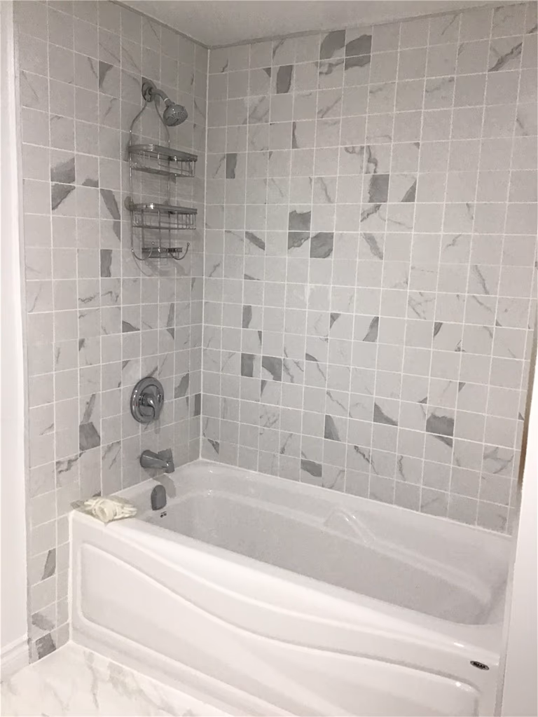 This Whitby basement renovation includes a sleek bathtub installation with a marble-pattern tile surround, creating a clean and contemporary bathroom design. The neutral-toned tiles, chrome fixtures, and built-in shelving add both style and practicality. Designed for comfort and durability, this upgraded basement bathroom enhances the functionality of the finished lower level space.