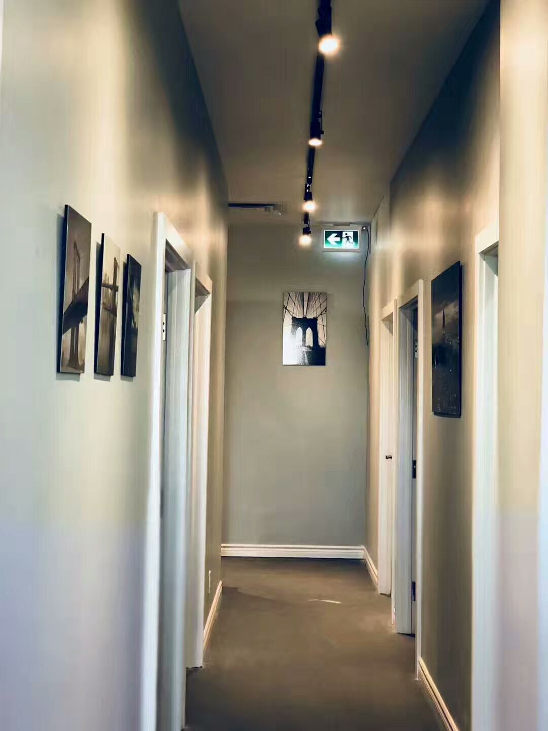 This image features an interior corridor completed as part of a cafeteria commercial renovation project in North York. The hallway is designed with clean wall finishes, framed wall art, and ceiling-mounted track lighting to ensure clear visibility and safe circulation for staff and customers. Doorway alignment and lighting placement support efficient movement between functional areas while maintaining a modern and professional atmosphere. This North York cafeteria commercial renovation highlights thoughtful space planning, lighting coordination, and code-conscious execution by a Toronto renovation company specializing in commercial interior renovations.