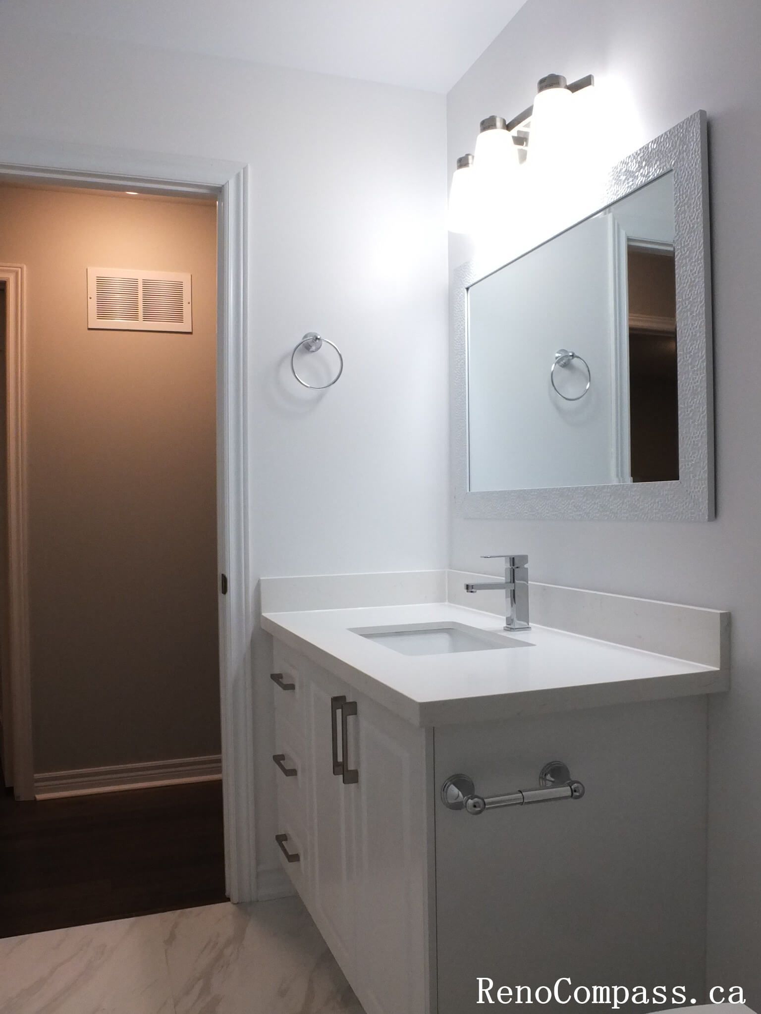 This Richmond Hill bathroom renovation features a sleek single-sink vanity with a quartz countertop, modern chrome faucet, and illuminated mirror lighting. Completed by a professional Toronto renovation company, the design emphasizes clean lines, efficient storage, and bright, balanced lighting. Neutral finishes and refined details create a fresh, contemporary bathroom space that enhances both functionality and visual appeal.