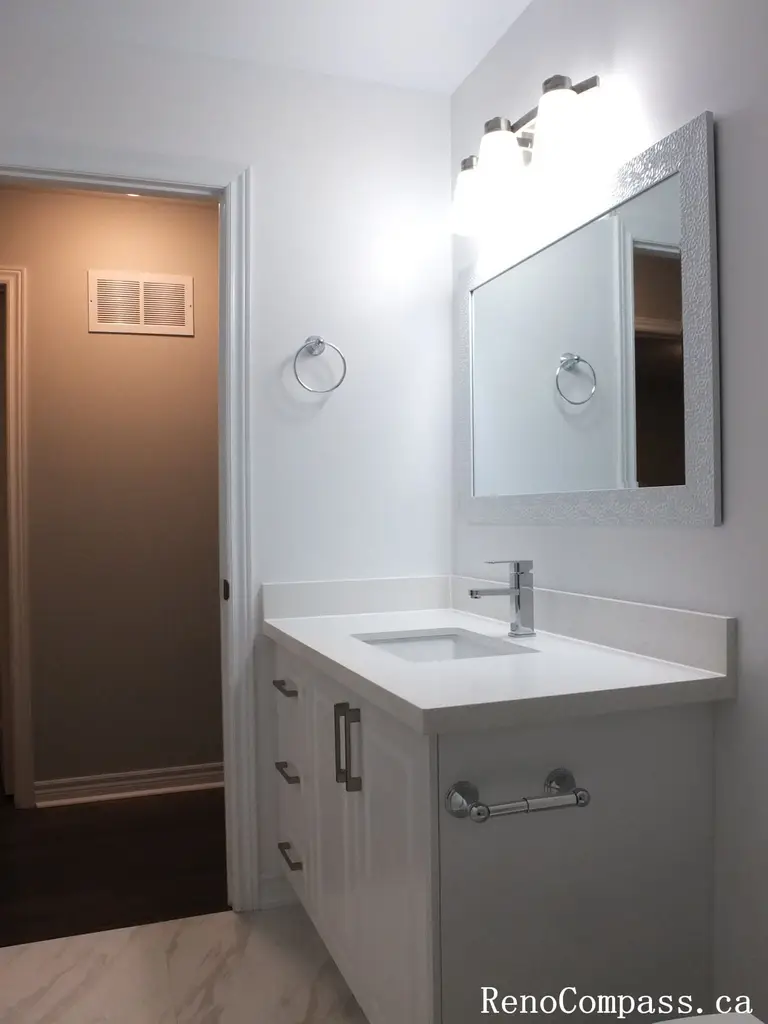 This Richmond Hill bathroom renovation features a sleek single-sink vanity with a quartz countertop, modern chrome faucet, and illuminated mirror lighting. Completed by a professional Toronto renovation company, the design emphasizes clean lines, efficient storage, and bright, balanced lighting. Neutral finishes and refined details create a fresh, contemporary bathroom space that enhances both functionality and visual appeal.