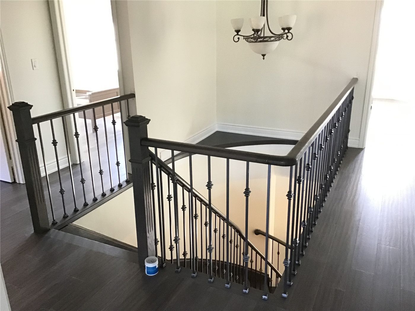 This Woodbridge interior renovation showcases a modern staircase upgrade featuring custom iron railings paired with dark hardwood flooring. The design enhances both safety and visual appeal, creating a clean and elegant transition between floors.