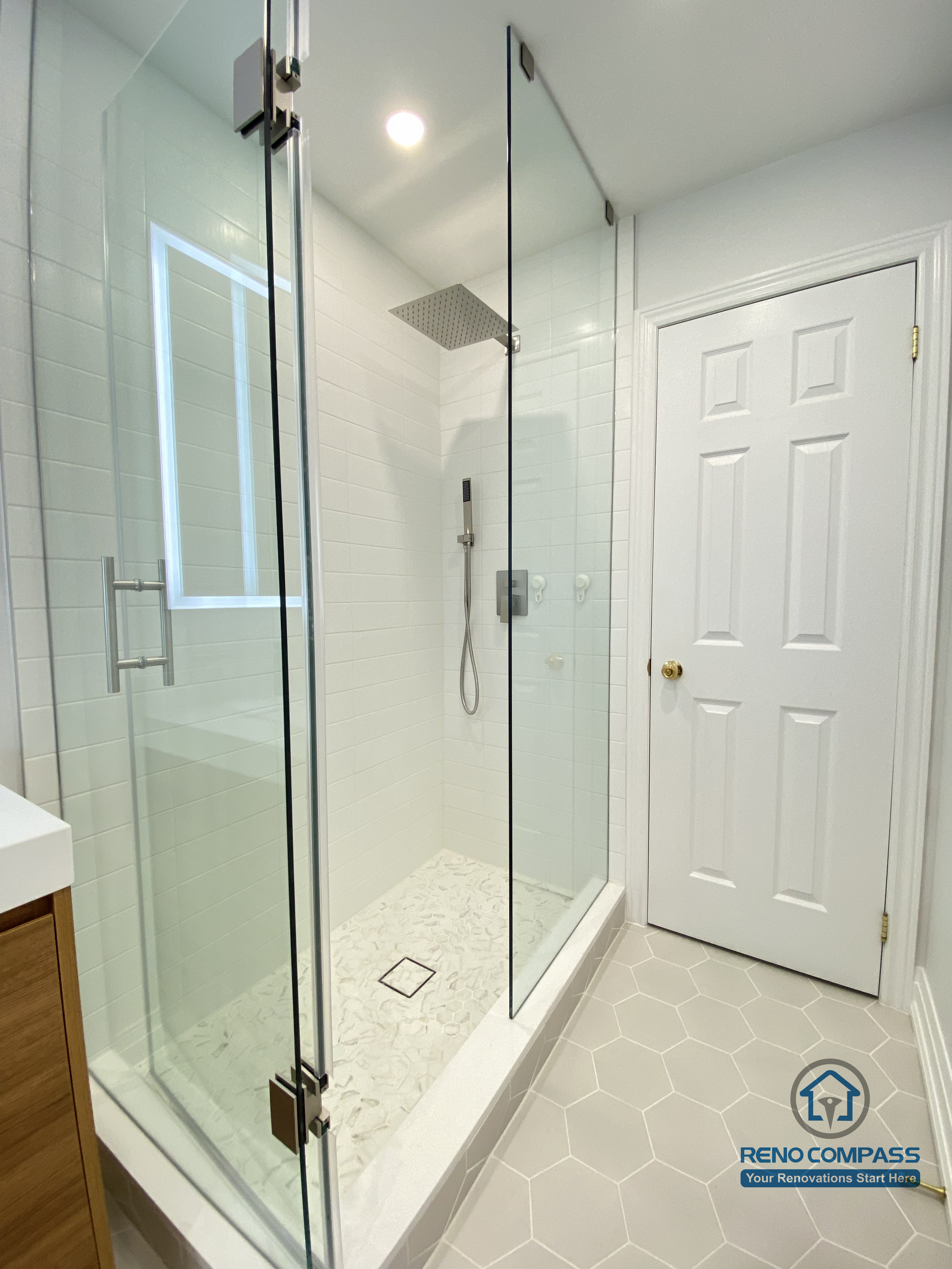 This Markham bathroom renovation highlights a custom double sink vanity designed to improve daily efficiency and long-term usability. The wood-tone vanity provides ample concealed storage while adding warmth and visual balance to the space. A full-width LED backlit mirror delivers even, glare-free lighting, enhancing functionality for everyday routines. Slip-resistant hexagon tile flooring improves safety and durability in a high-moisture environment, while neutral wall tones maintain a clean, timeless appearance. Completed by a Toronto renovation company, Reno Compass Inc., this bathroom renovation reflects careful space planning, material coordination, and a modern, practical design approach for Markham homes.