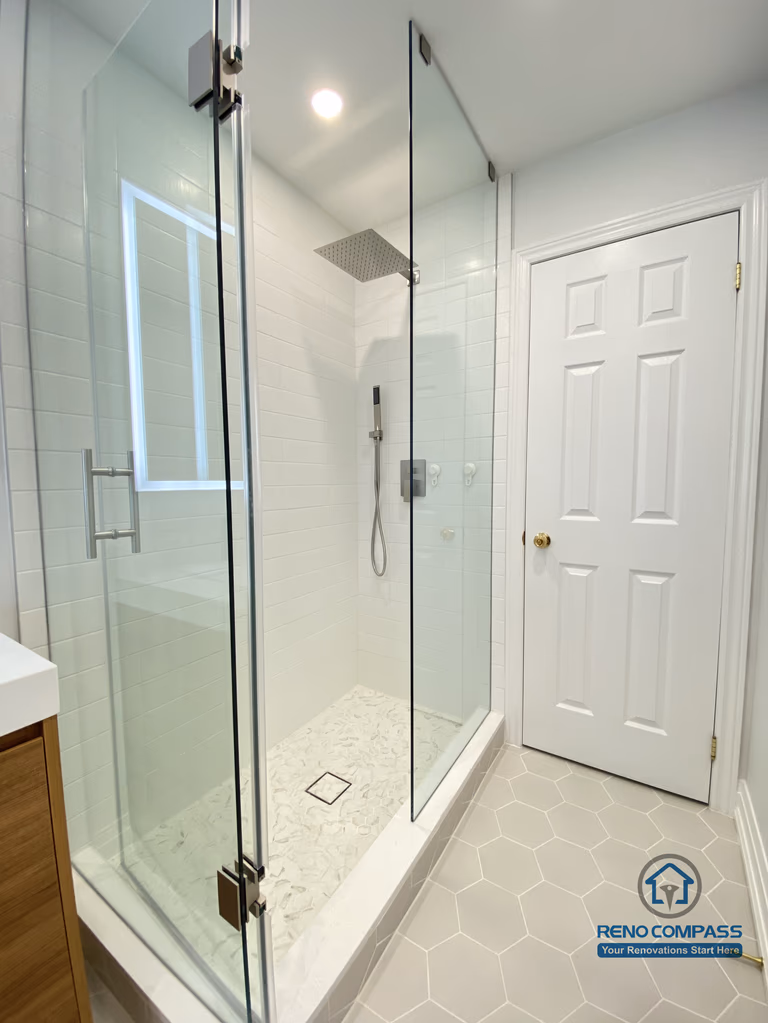 This Markham bathroom renovation highlights a custom double sink vanity designed to improve daily efficiency and long-term usability. The wood-tone vanity provides ample concealed storage while adding warmth and visual balance to the space. A full-width LED backlit mirror delivers even, glare-free lighting, enhancing functionality for everyday routines. Slip-resistant hexagon tile flooring improves safety and durability in a high-moisture environment, while neutral wall tones maintain a clean, timeless appearance. Completed by a Toronto renovation company, Reno Compass Inc., this bathroom renovation reflects careful space planning, material coordination, and a modern, practical design approach for Markham homes.