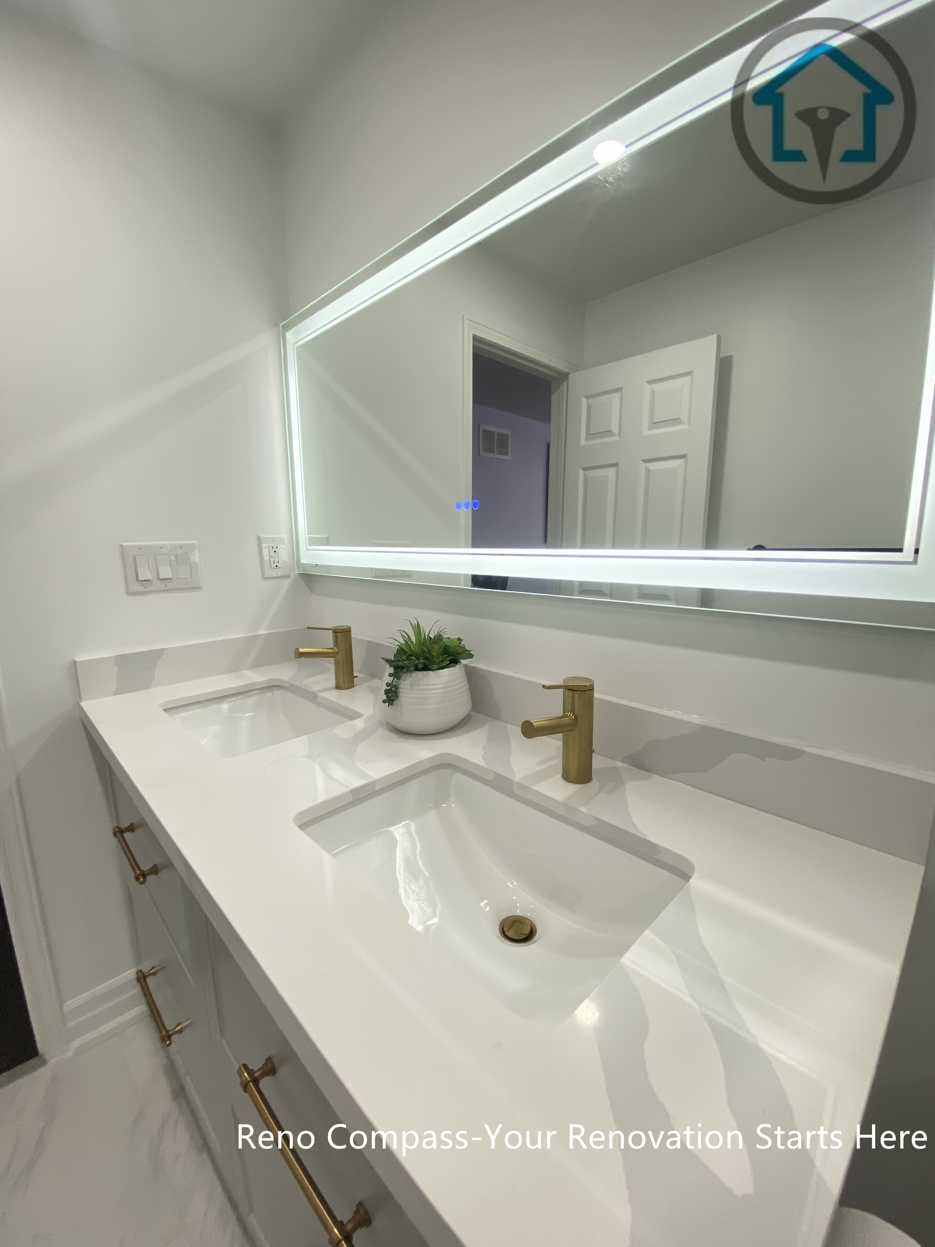 Close-up view of a modern double vanity installed as part of a Pickering bathroom renovation. The design features an integrated white quartz countertop with dual undermount sinks, brushed brass faucets, and a full-width LED backlit mirror. Clean lines, neutral tones, and balanced lighting create a functional yet refined vanity area suitable for daily family use.