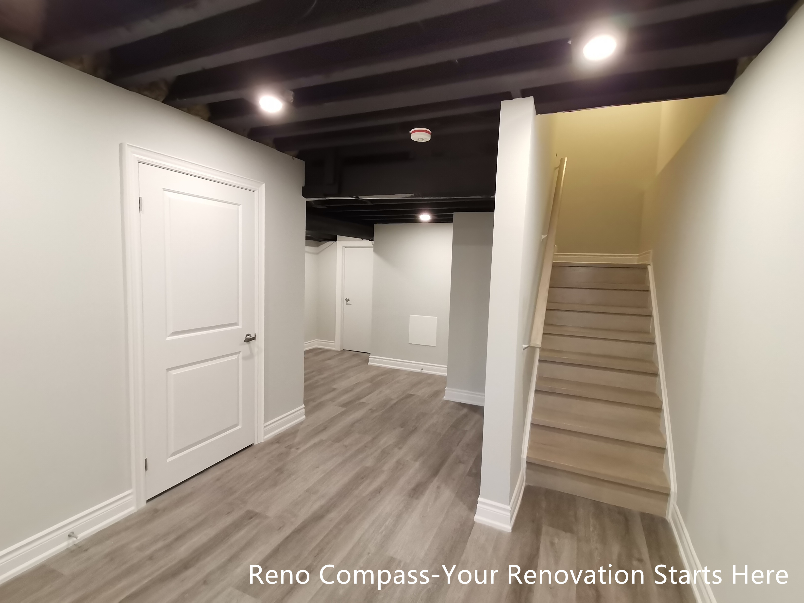 This Vaughan basement renovation showcases a well-organized layout featuring an open staircase connection, dedicated functional zones, and an industrial-style sprayed black ceiling. Durable flooring, clean wall finishes, and recessed lighting create a cohesive and practical lower-level space. The design clearly separates circulation, storage, and activity areas while maintaining an open and uncluttered feel. Designed and completed by Reno Compass, this basement renovation emphasizes spatial efficiency, visual continuity, and long-term usability.