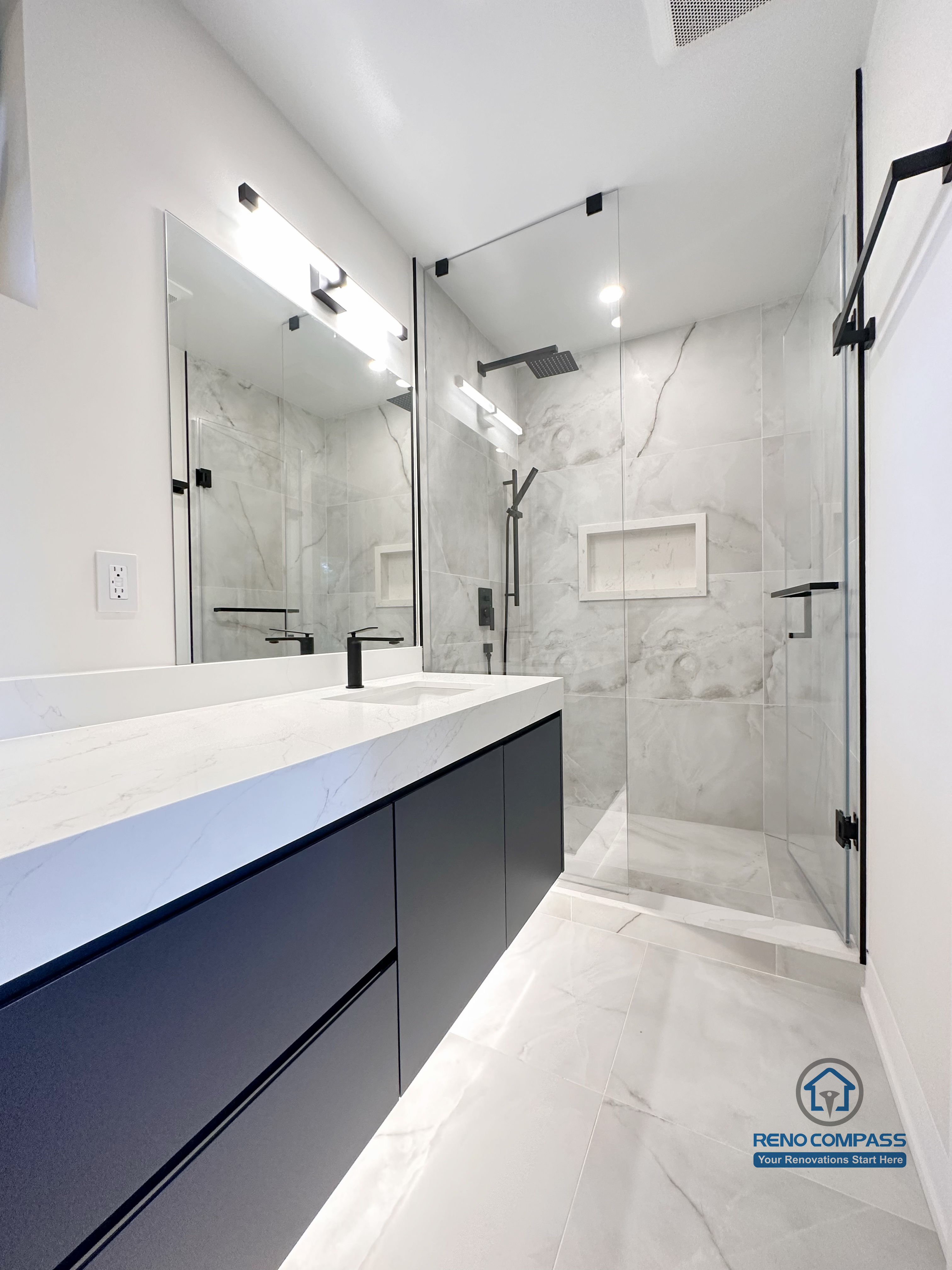 Modern bathroom renovation in Toronto showcasing a frameless glass walk-in shower, large-format marble-look tiles, floating custom vanity, and matte black fixtures. Completed by a professional Toronto renovation company with a focus on clean lines, durability, and contemporary design.