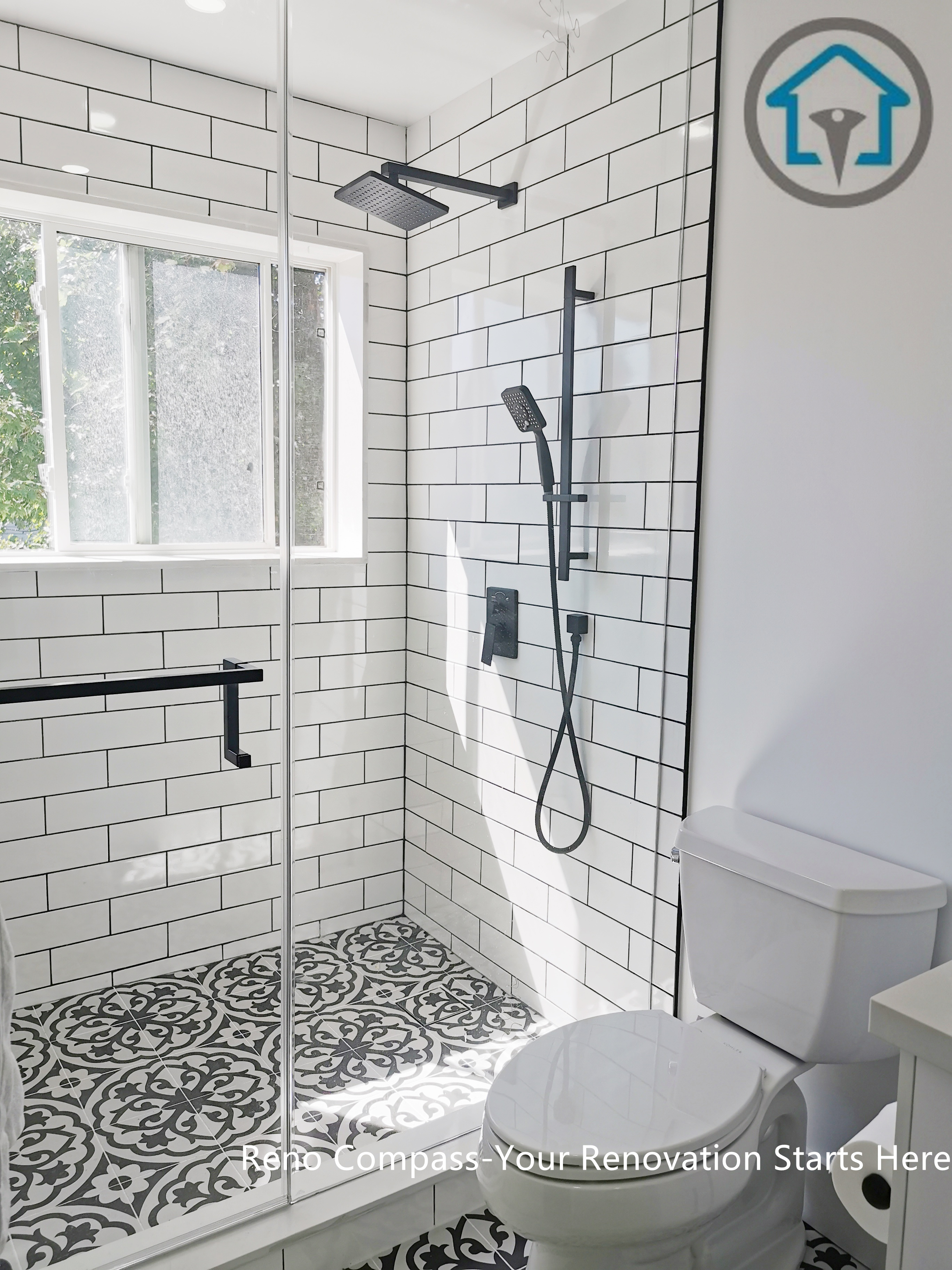 This Ajax bathroom renovation features a bright walk-in shower design with classic white subway tiles and bold patterned floor tiles. The black fixtures and glass shower enclosure create a clean contrast, while the window brings in natural light to enhance the overall openness. A timeless black-and-white palette paired with modern details delivers both visual impact and everyday functionality.
