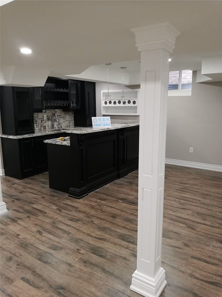 This Richmond Hill basement renovation features a stylish modern home bar with dark cabinetry, a mosaic tile backsplash, and warm wood-look flooring. The elegant white column and custom bar design create a perfect entertainment space with contemporary finishes.