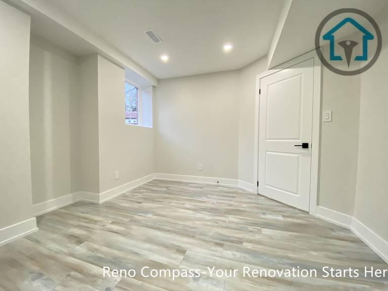 This Stouffville basement renovation showcases newly installed vinyl plank flooring, smooth drywall finishes, and modern interior doors with black hardware. The clean layout and neutral color palette create a bright, functional basement space suitable for bedroom, office, or family room use, completed by Reno Compass Inc.