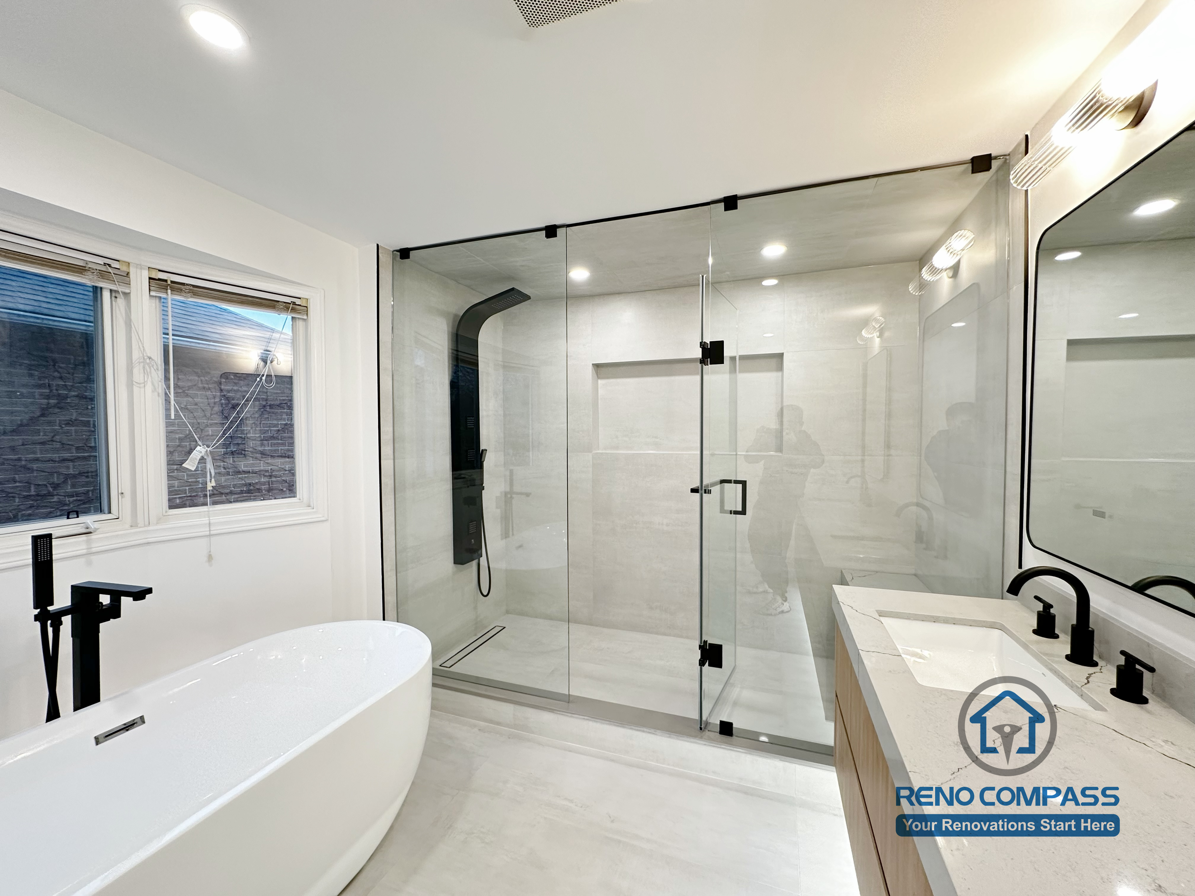 Completed Oakville bathroom renovation featuring a freestanding bathtub, frameless glass shower enclosure, custom vanity, and modern fixtures, completed by a professional Toronto renovation company.